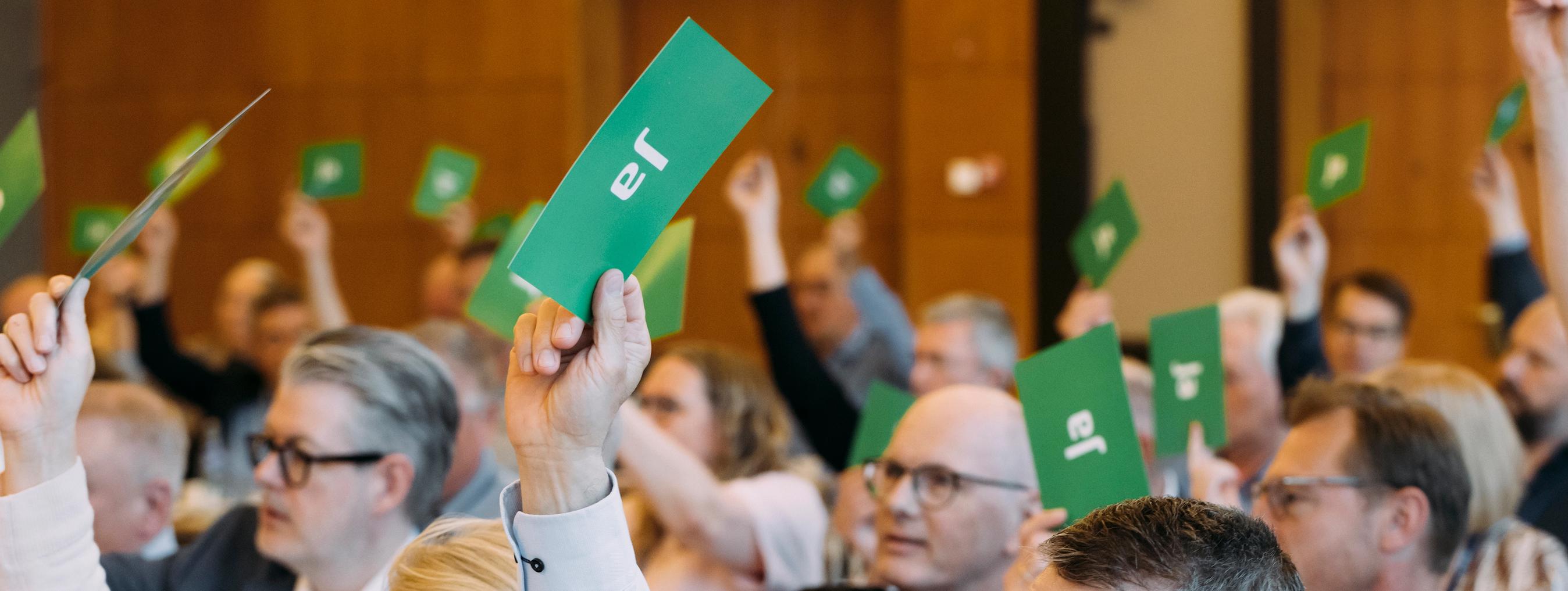 Medlemmer af FDMs repræsentantskab rækker armen i vejret og afgiver stemme til valg