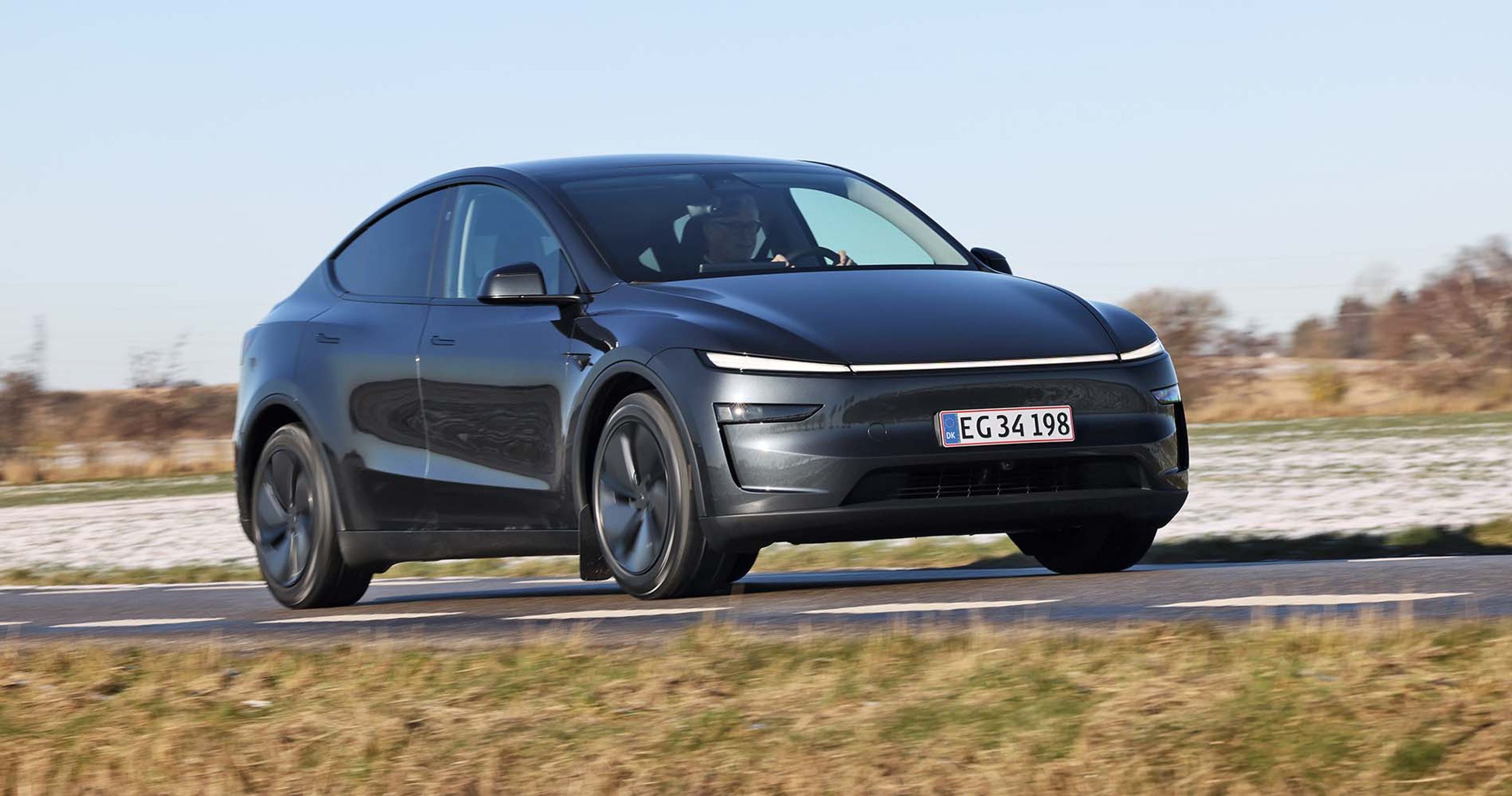 Tesla Model Y kører på landevej med sne i baggrunden