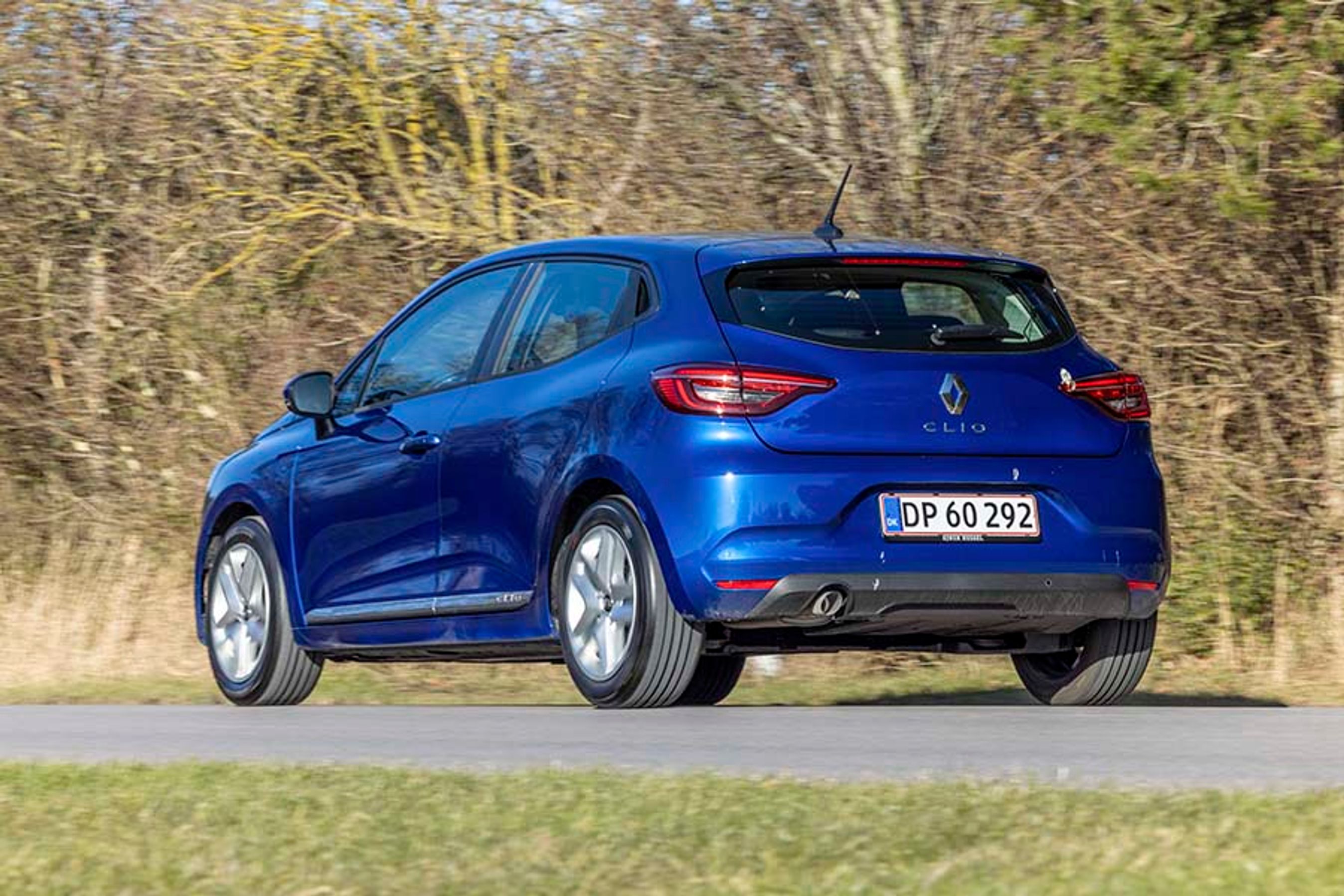 En blå Renault Clio set bagfra kører på landevej