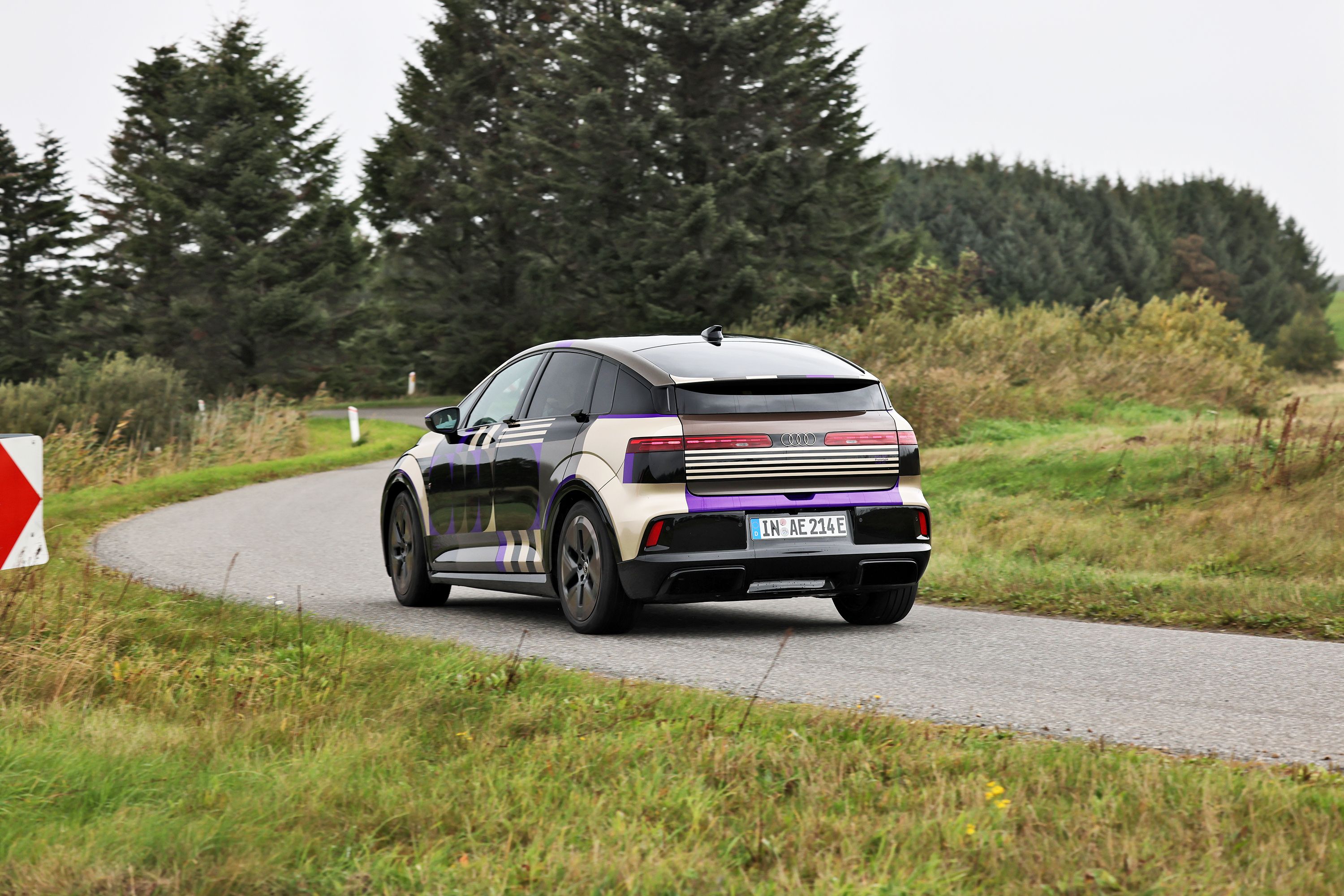 Audi A2 e-tron 140 kW set bagfra på dansk landevej med grønne træer i baggrunden. 
