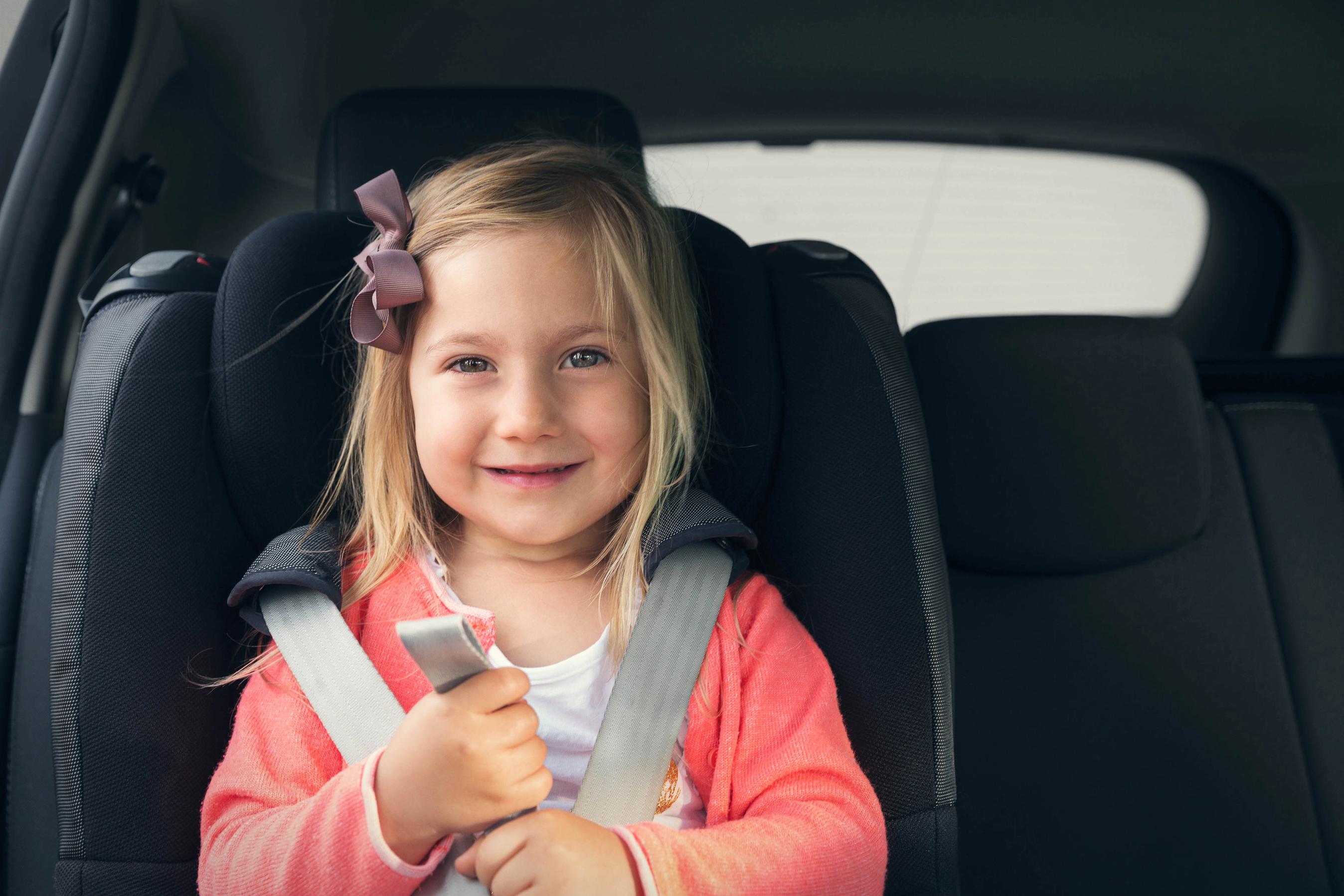 en pige sidder i en autostol i en bil