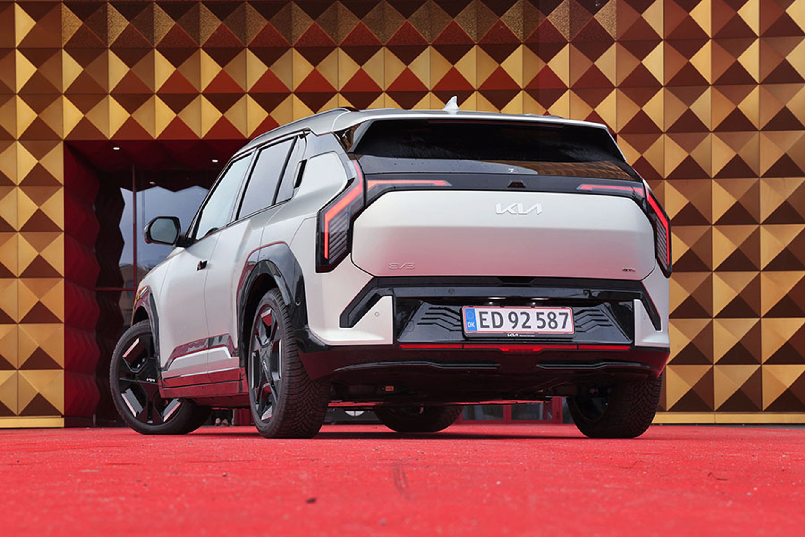 Kia EV3 elbil set bagfra, mens den holder foran guldfarvet bygning