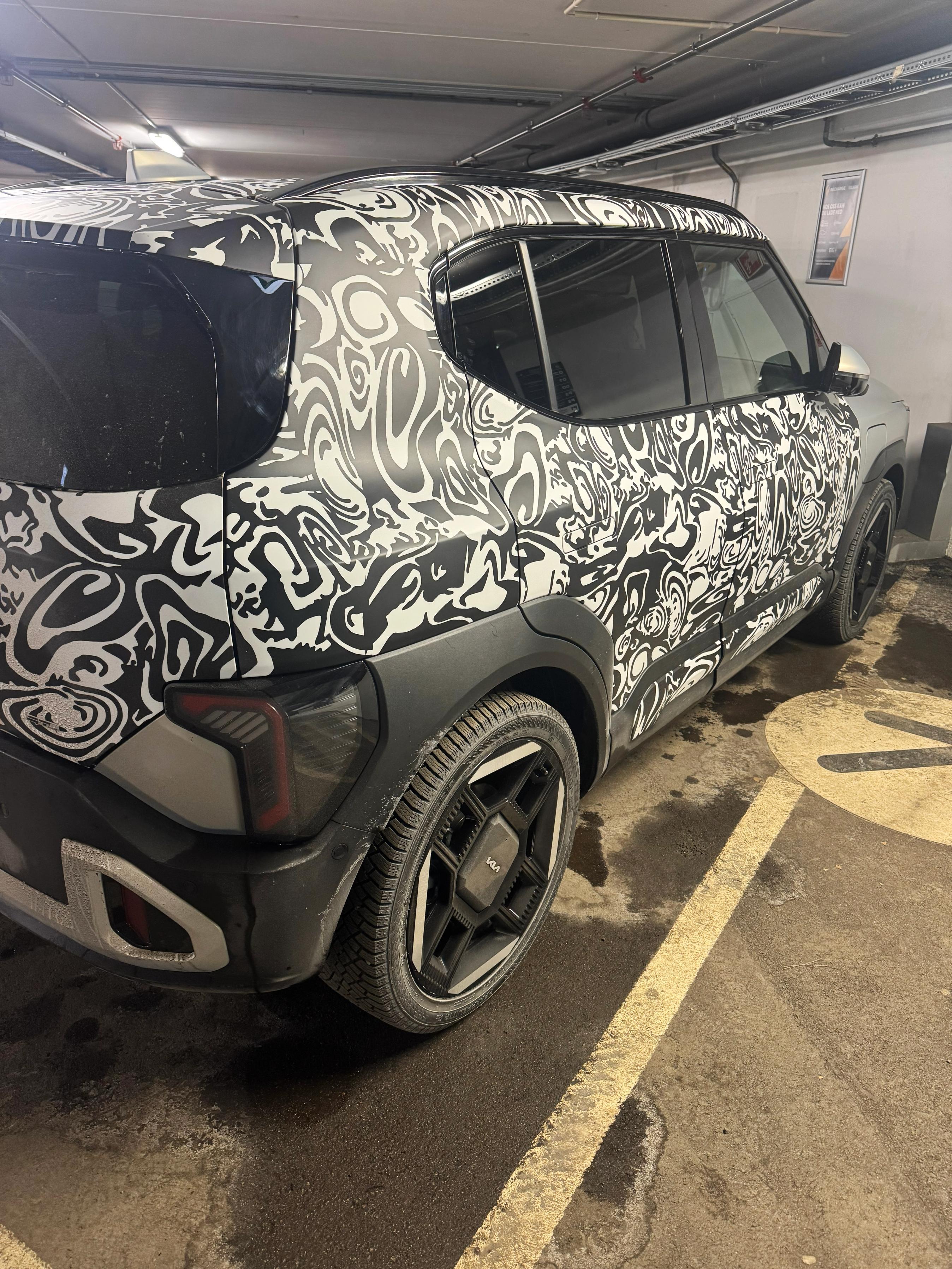 Kia EV2 i parkeringskælder med sort-hvid kamuflage indpakning.