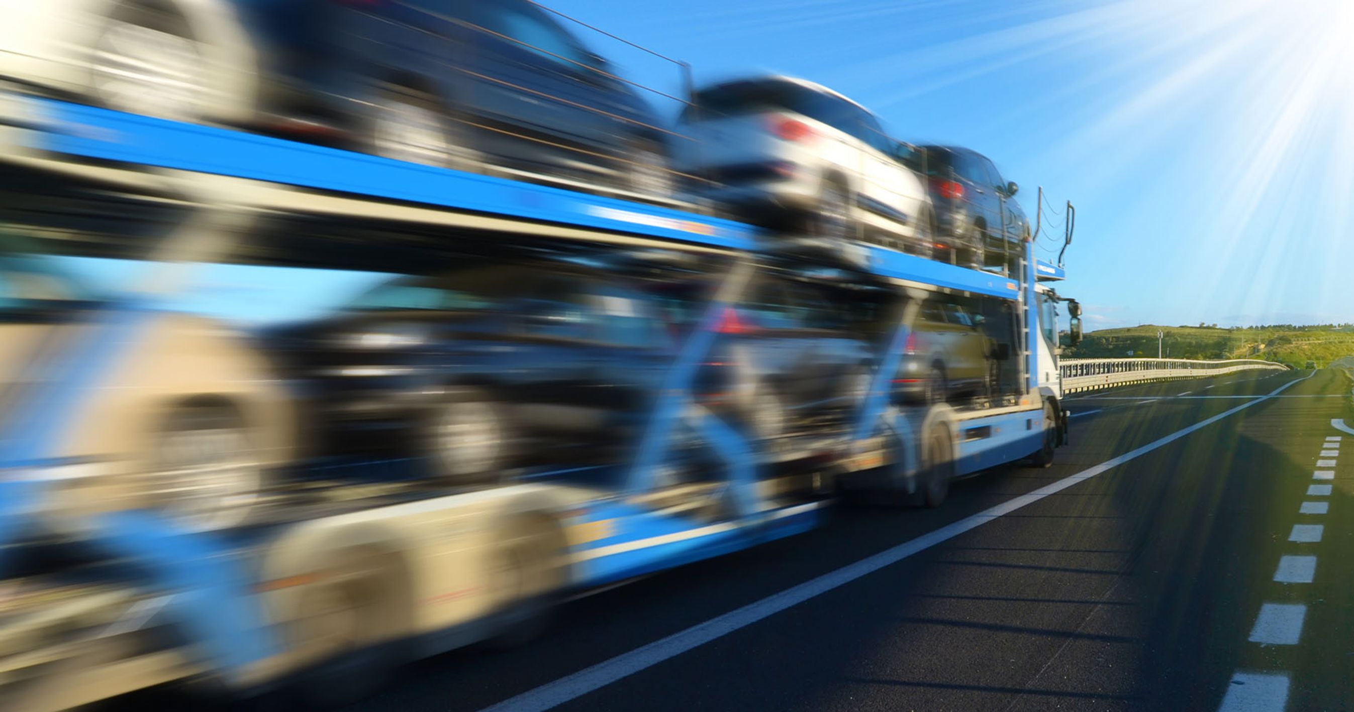 Biler på en autotransporter der kører på en landevej.