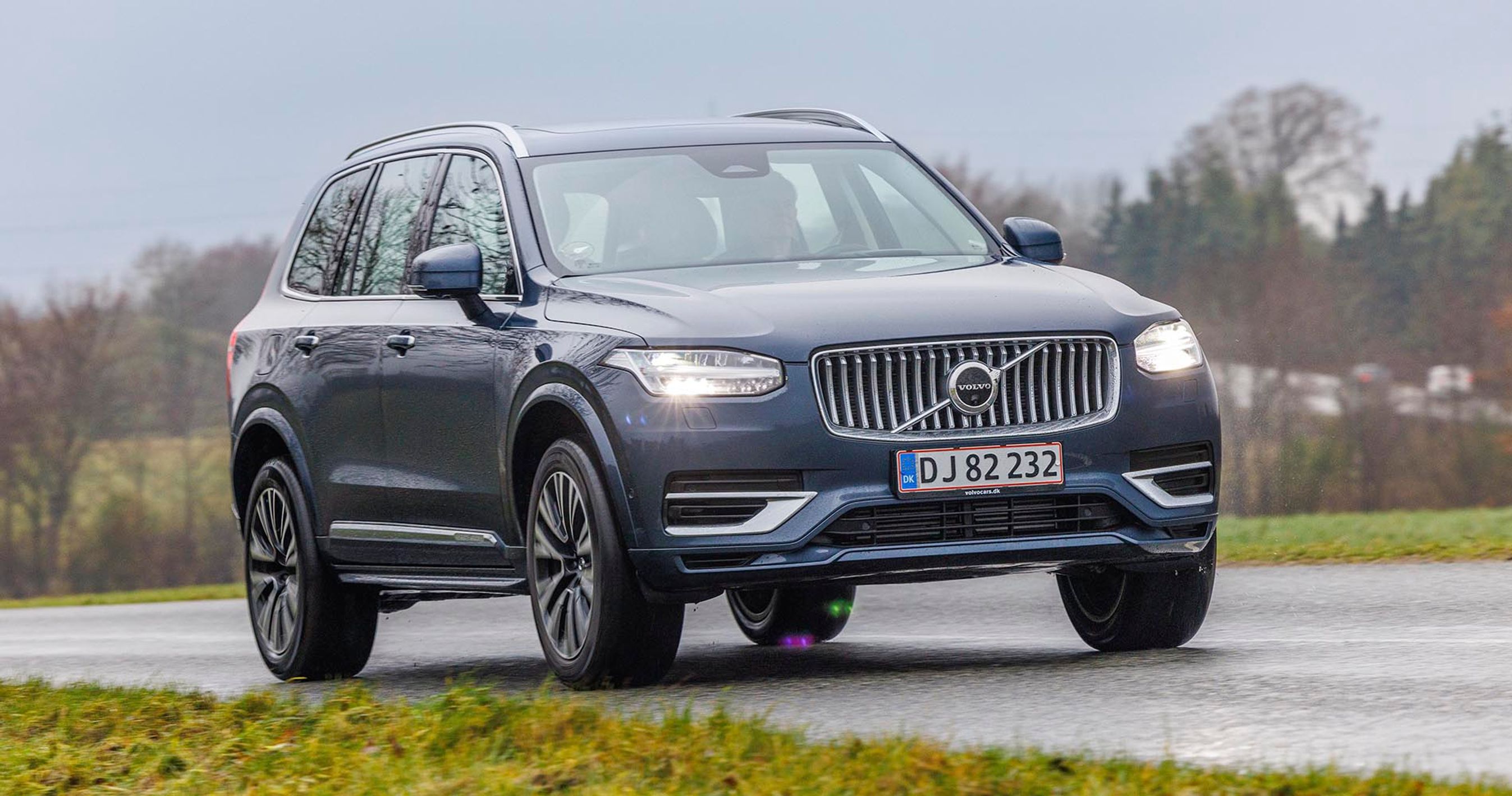 E mørke Volvo XC90 kører på landevej på en gråvejrsdag