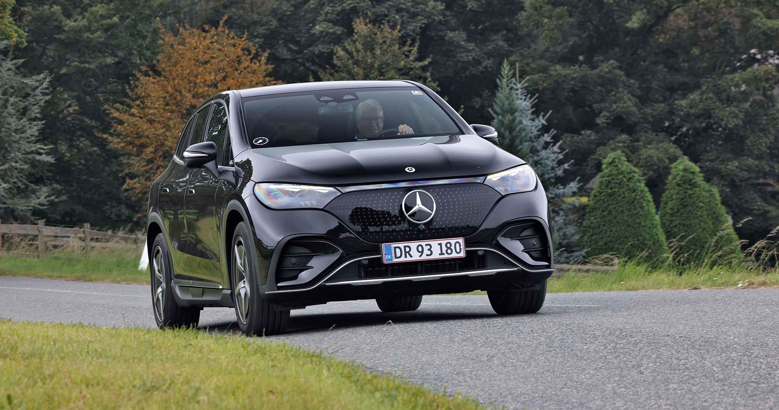 Elbilen Mercedes EQE SUV kører på en landevej med træer i baggrunden.