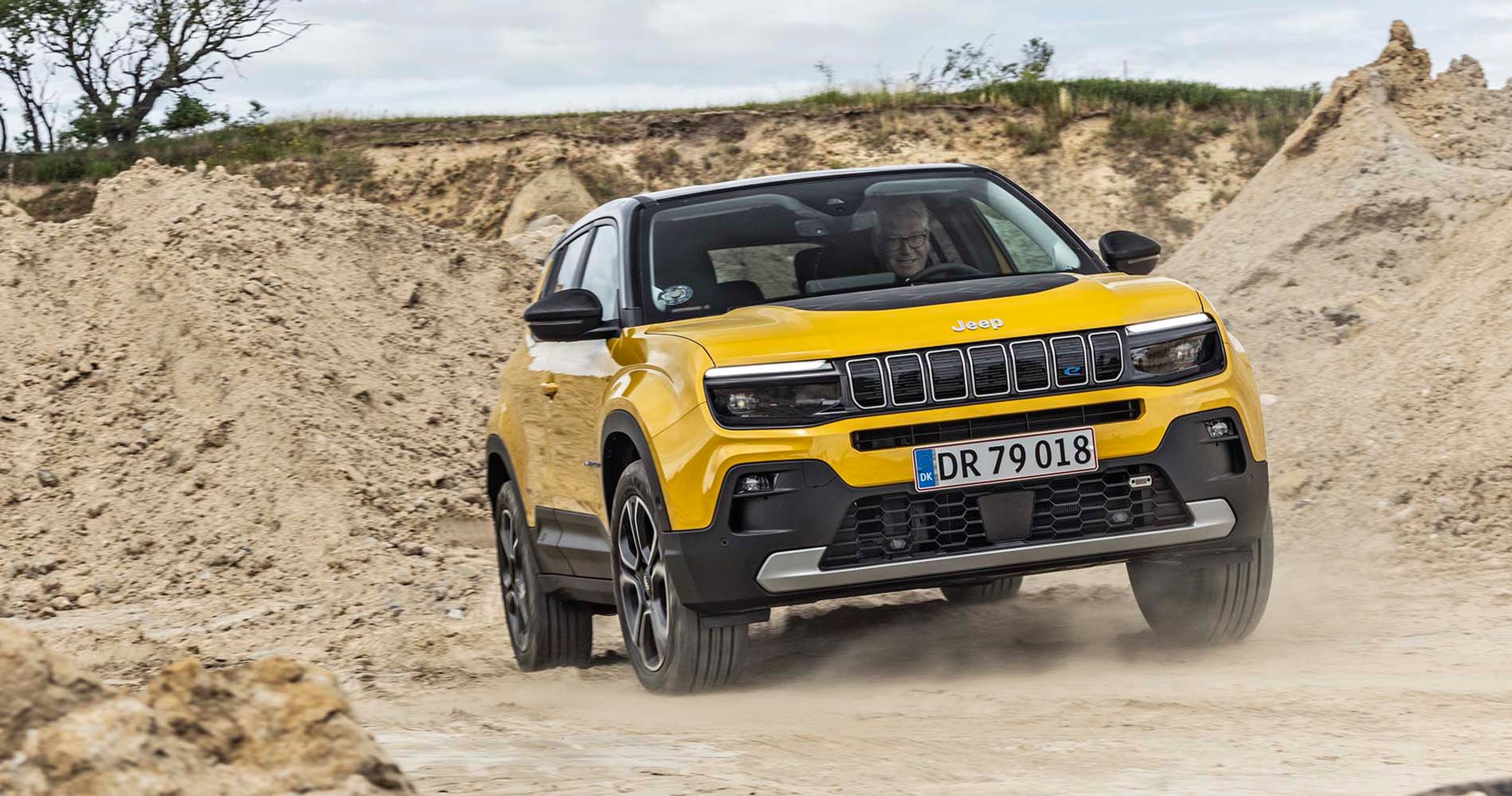 Gul Jeep Avenger kører på en grusvej