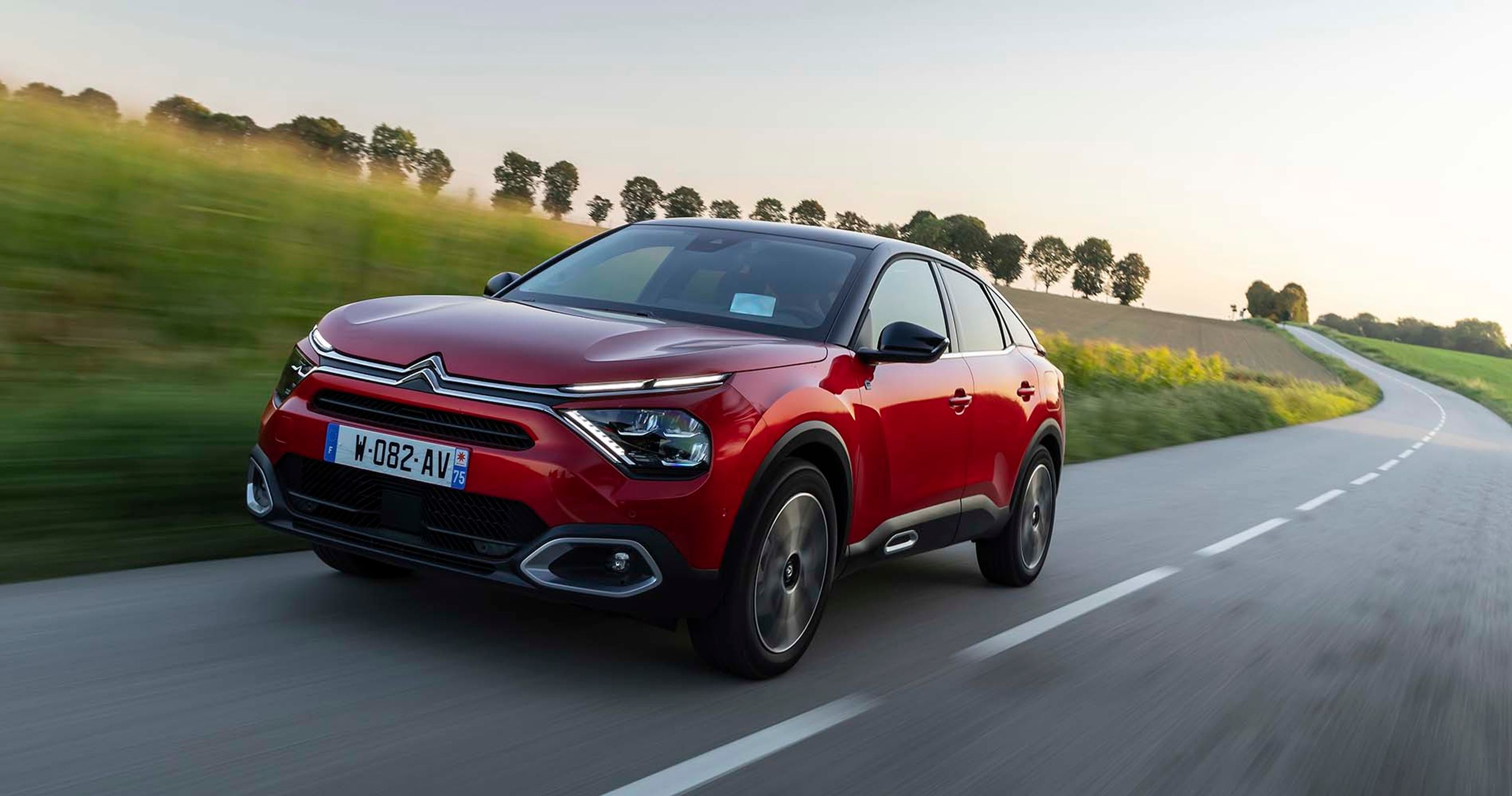 Citroën Ë-C4 kører i et sving på en landevej ved solnedgang.