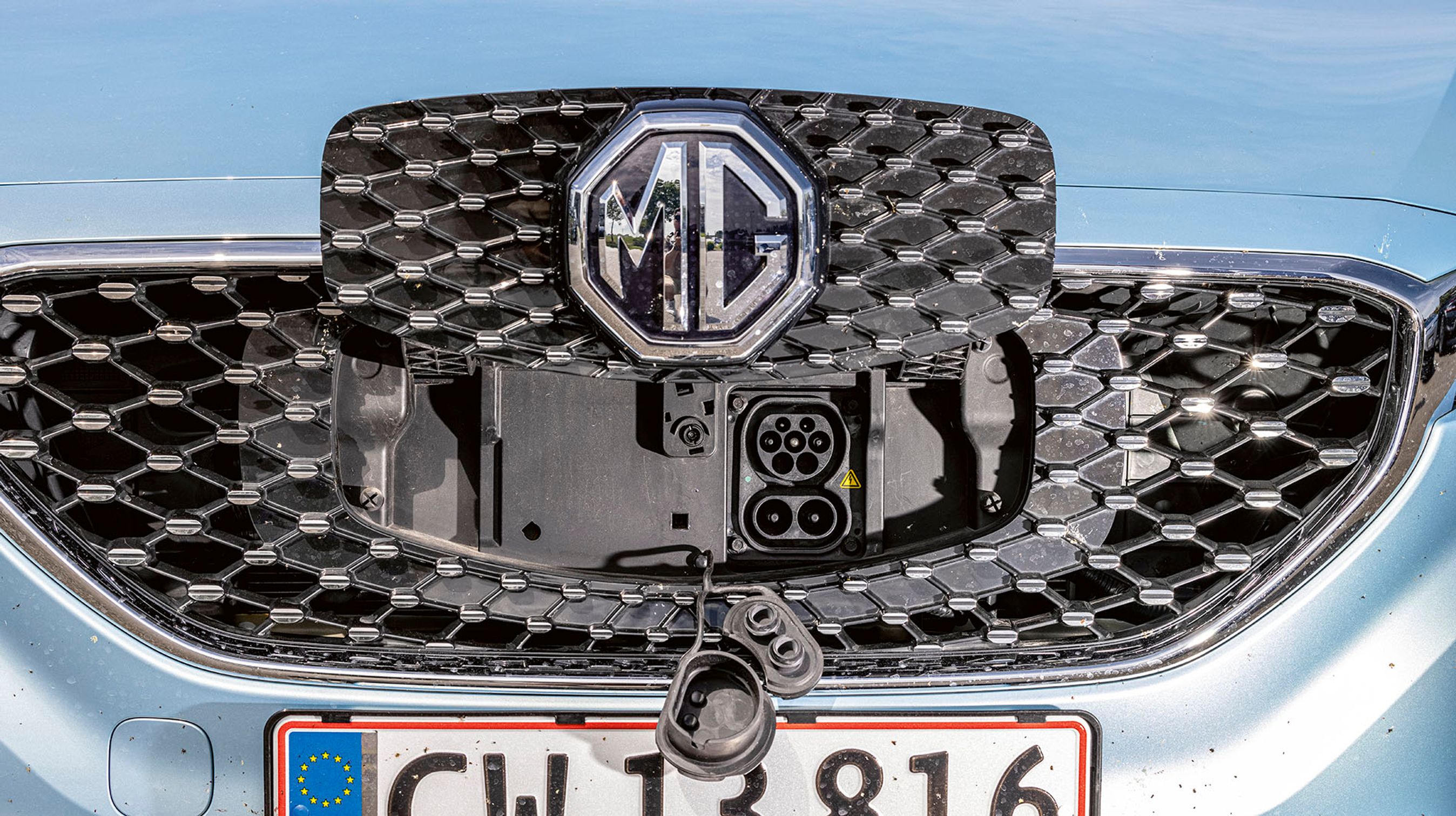 Ladestikket er placeret bag en klap i fronten af bilen. Der er et CCS-Combo-stik, men hjemme kan man kun lade med en enkelt fase. Bilen skal være låst, før den lader, og så lyser MG-logoet op imens.