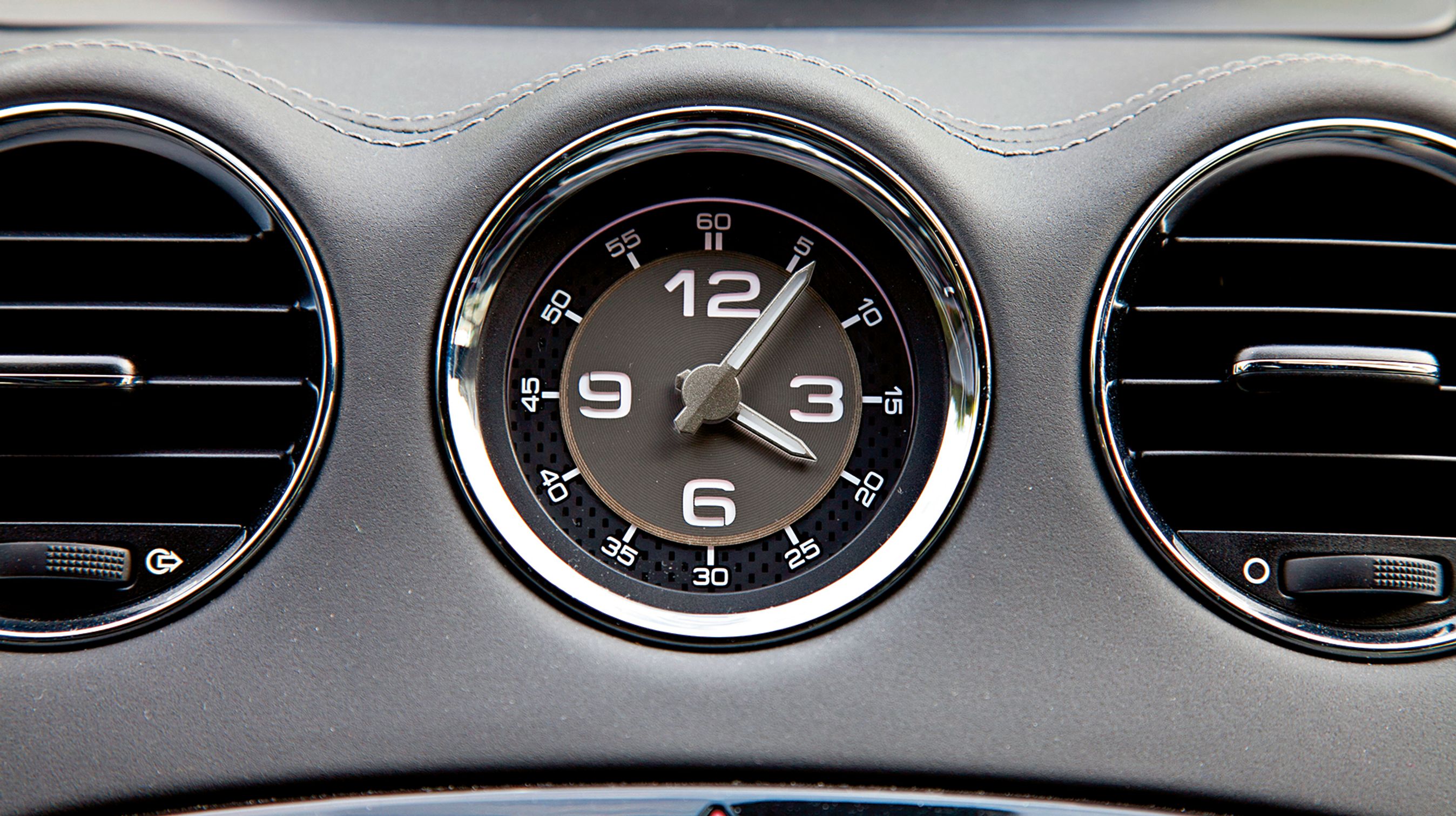 Et gammeldags viser-ur er placeret mellem ventilationsdyserne over radioen.