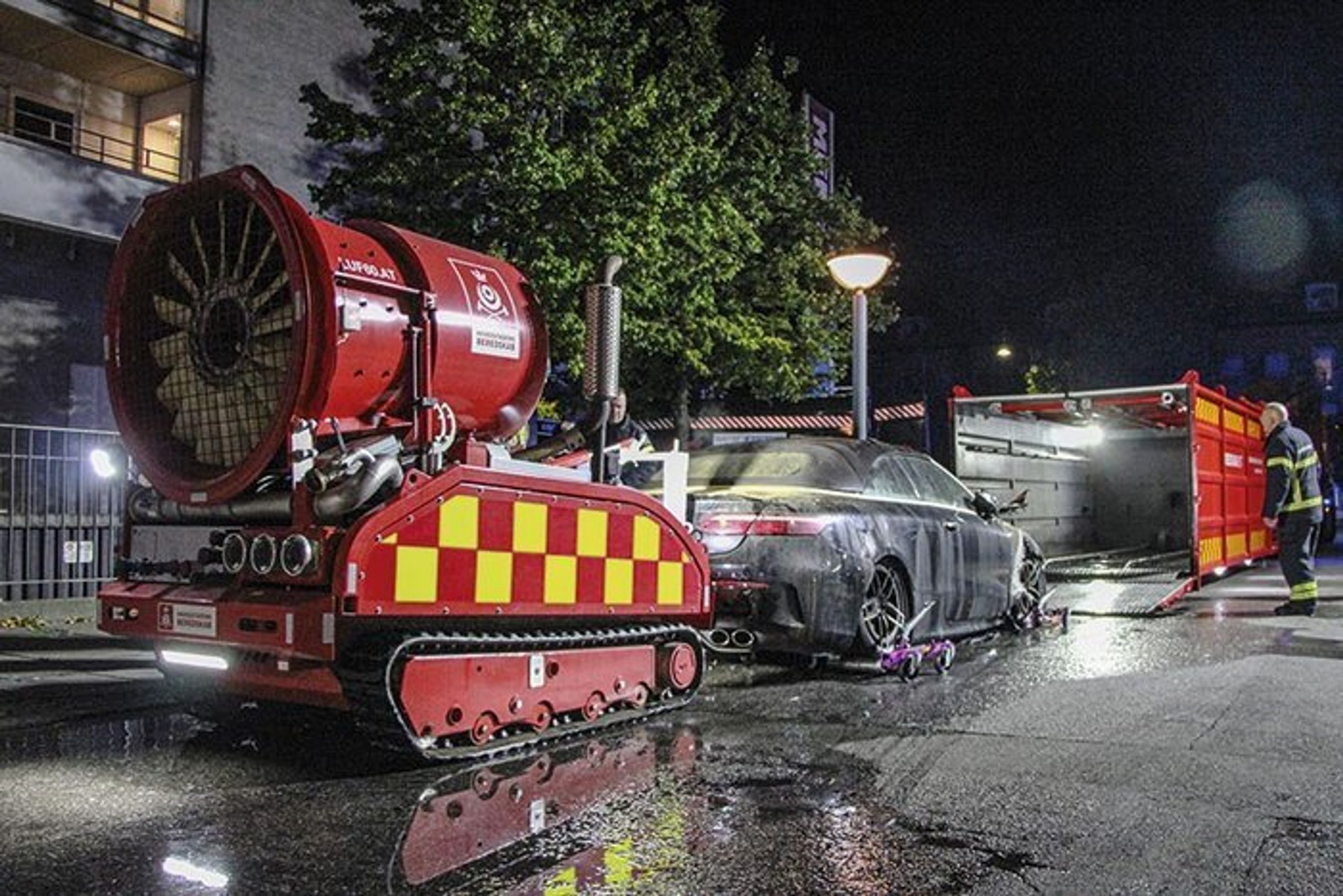 En udbrændt mildhybridbil er med robot skubbet op af en p-kælder og er her på vej ind i en særlig container