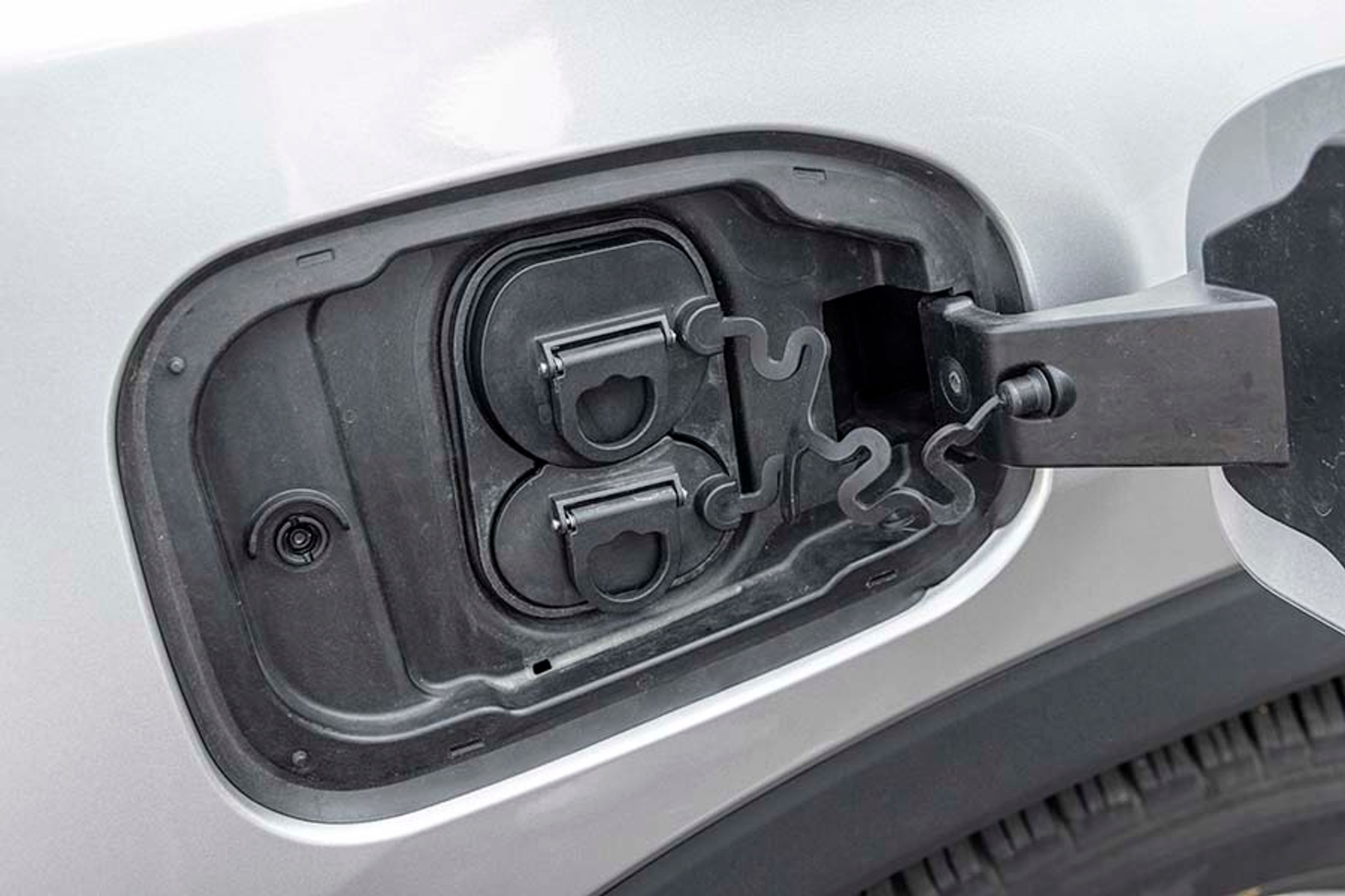 Ladestikket er placeret ved højre forhjul og har to gummipropper, der skal fjernes, før man kan lade. Bilen lader kun med én fase (3,7 kW), og det tager dermed 19 timer at få strøm på bilen igen. Der er ikke udløser til kablet, ej heller lys.