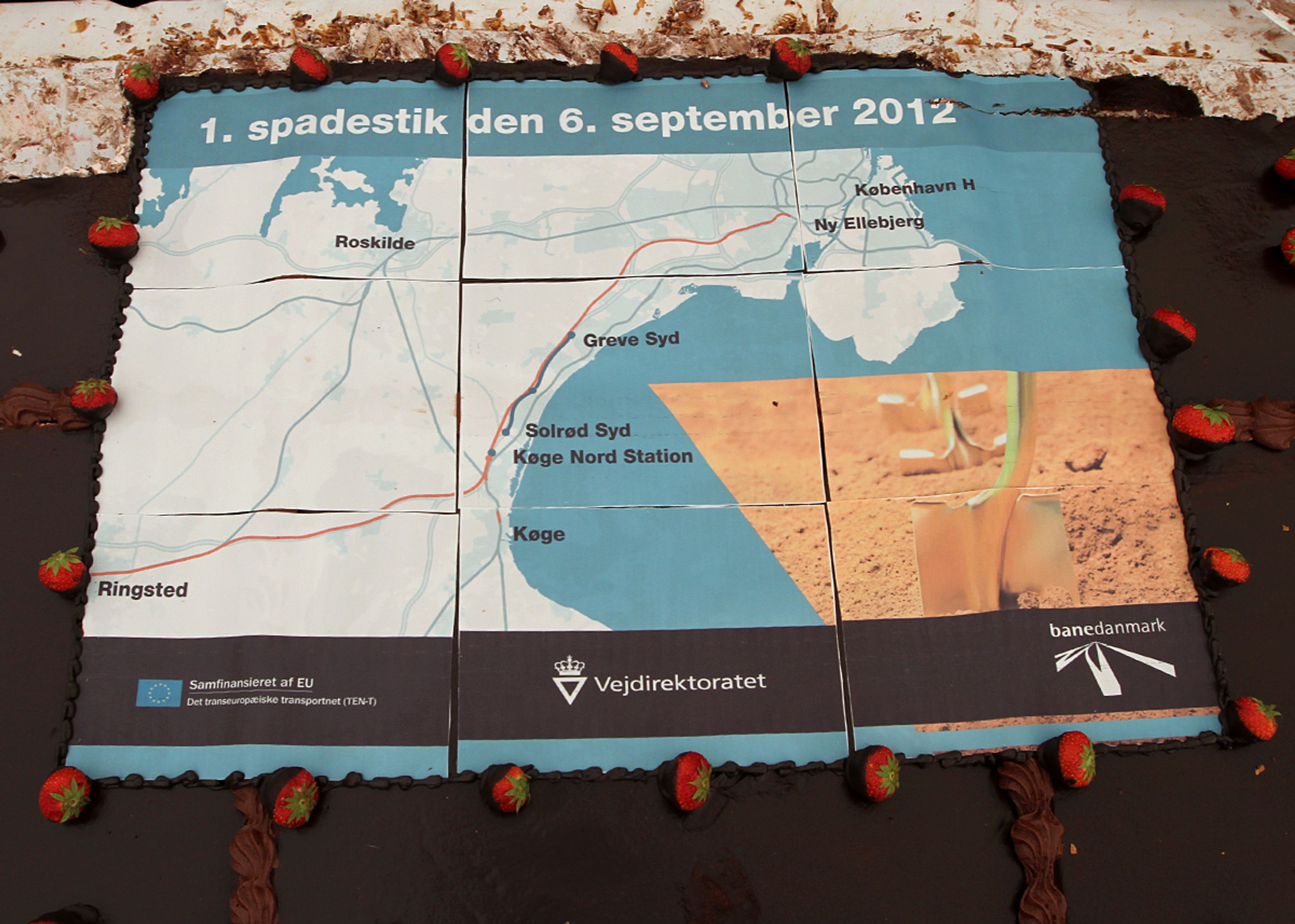 De indbudte fagfolk, politikere og lokale beboere blev budt på en gigantisk kage, da milliardprojektet blev sat i gang. Glassuren viser den udvidede motorvejsstrækning med grønblå og den nye jernbane med rød.