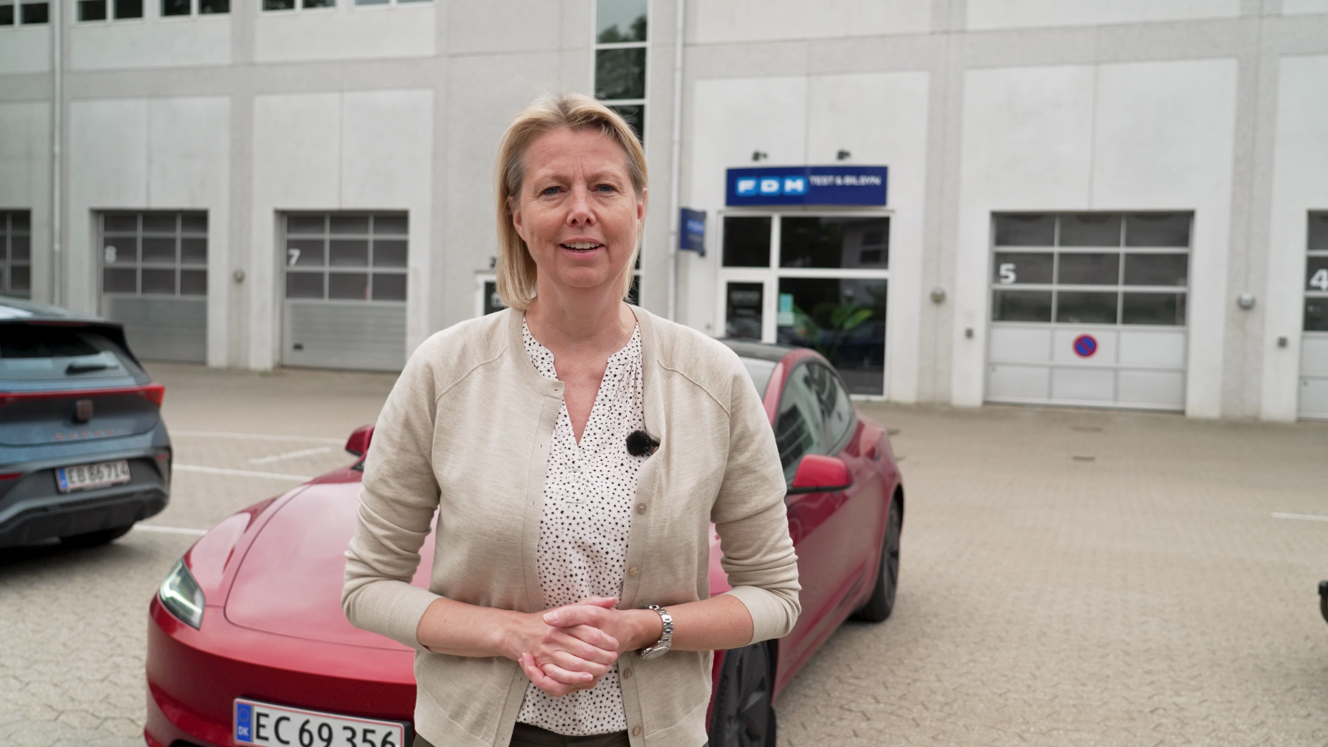FDMs direktør Stina Glavind foran en Tesla Model 3 med FSD Supervised.