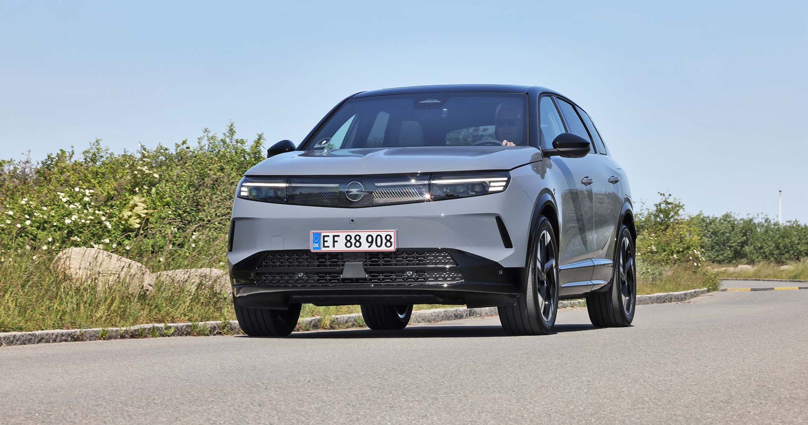 Opel Grandland kører i sving på vej med blå himmel i baggrunden