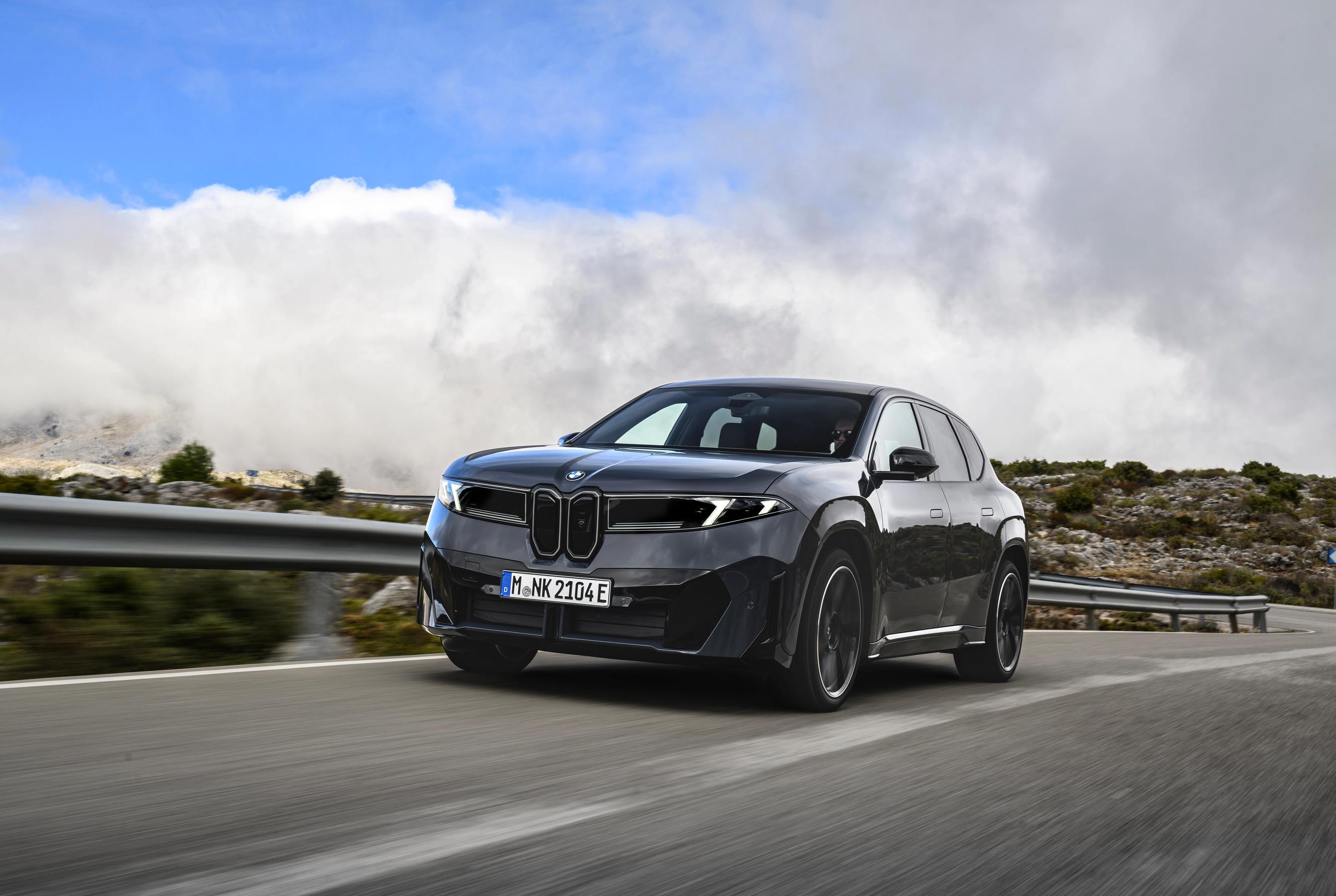 BMW iX3 set forfra, mens den kører på en vej med klipper og autoværn i baggrunden