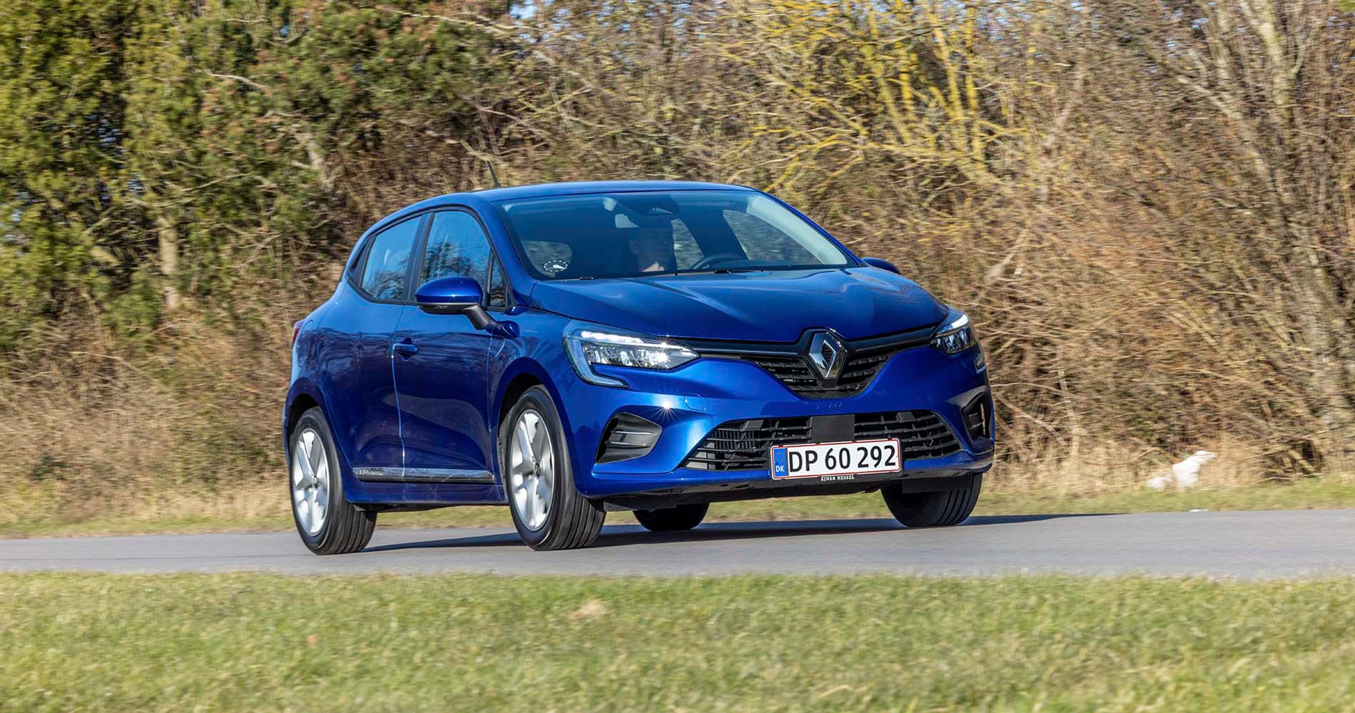 En blå Renault Clio kører på en landevej med træer i baggrunden