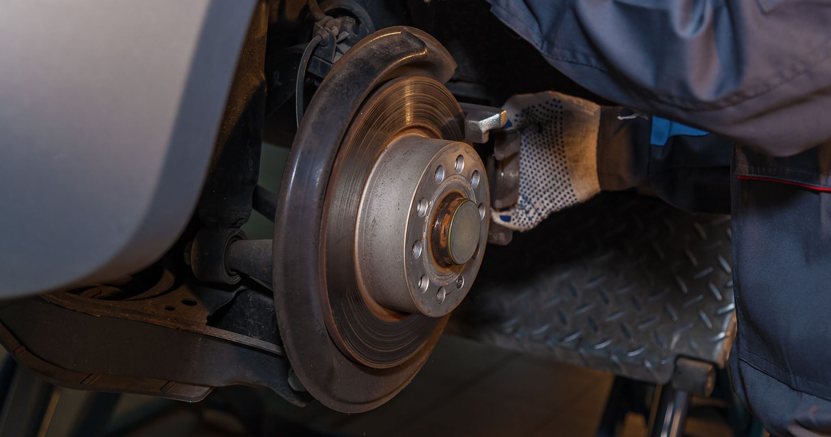 Rusten bremseskive monteret på bil. Mekaniker rører ved skiven.