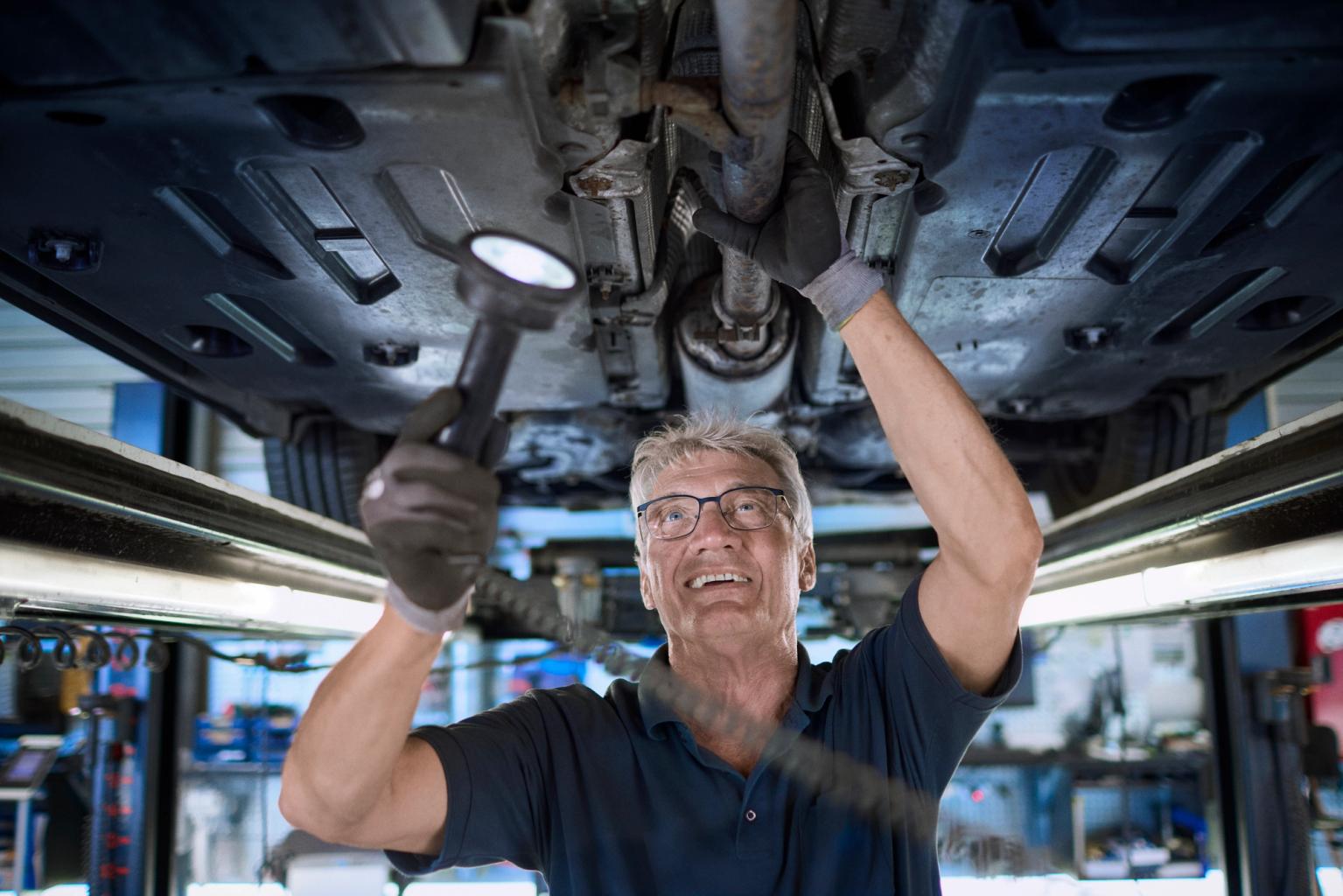 FDM medarbejder tjekker undervognen på en bil med lommelygte