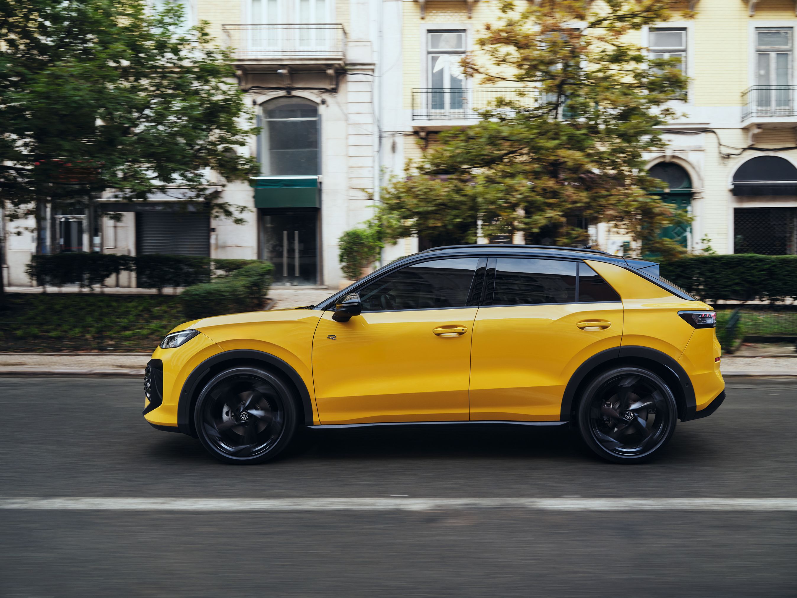 Gul VW T-Roc kører i byen. Man ser bilen fra siden