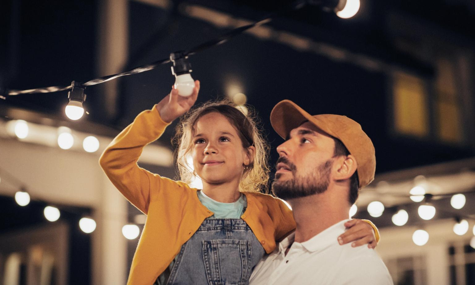 Far og datter sætter lyskæder op i haven med rabat fra DCC Energi