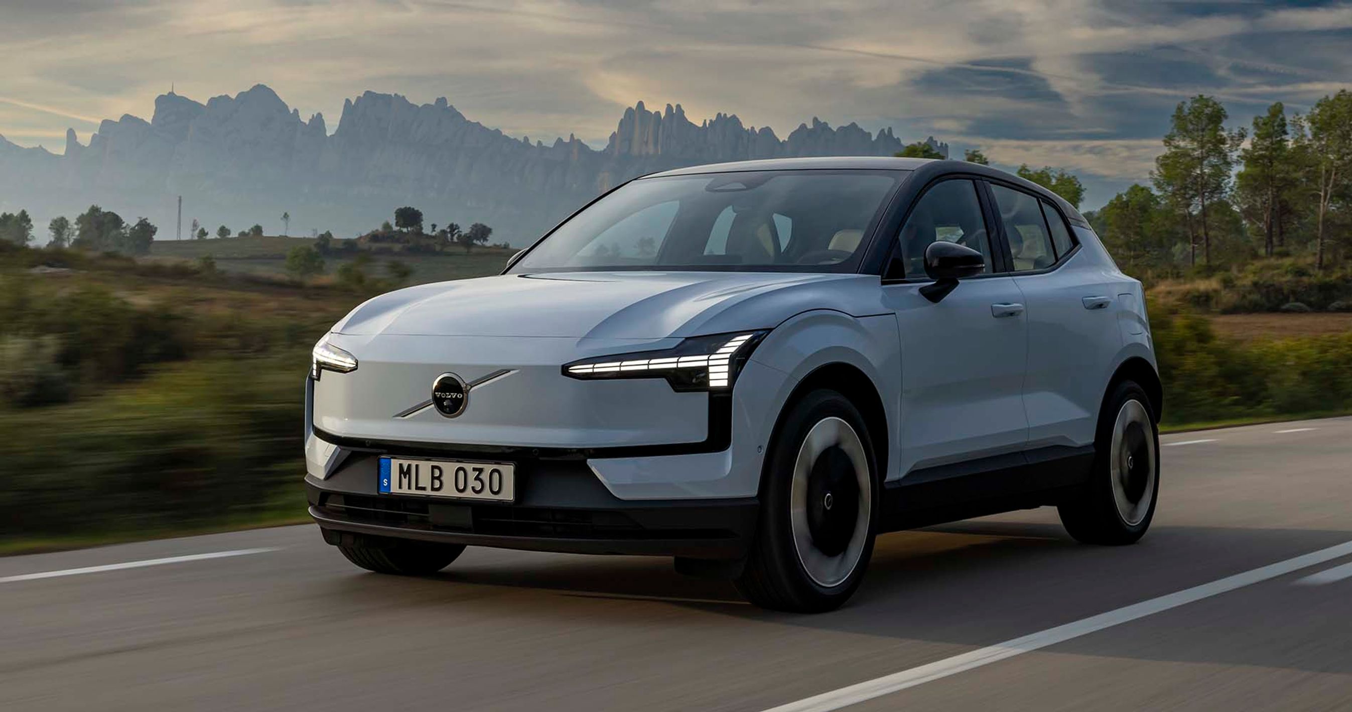 Elbilen Volvo EX30 kører på vej med bjerge i baggrunden.