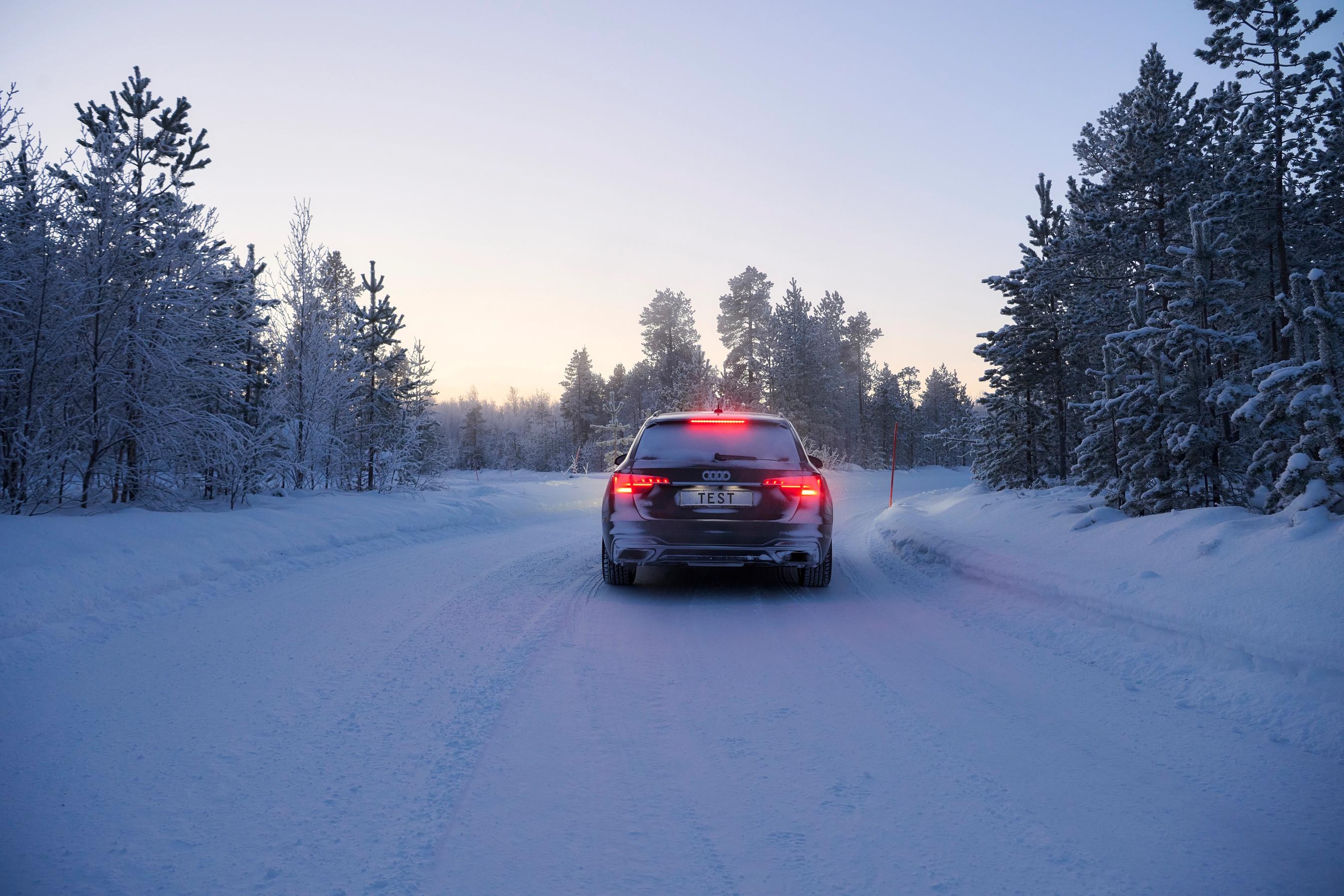 Bil holder stille på snedækket vej i Sverige med træer i baggrunden.