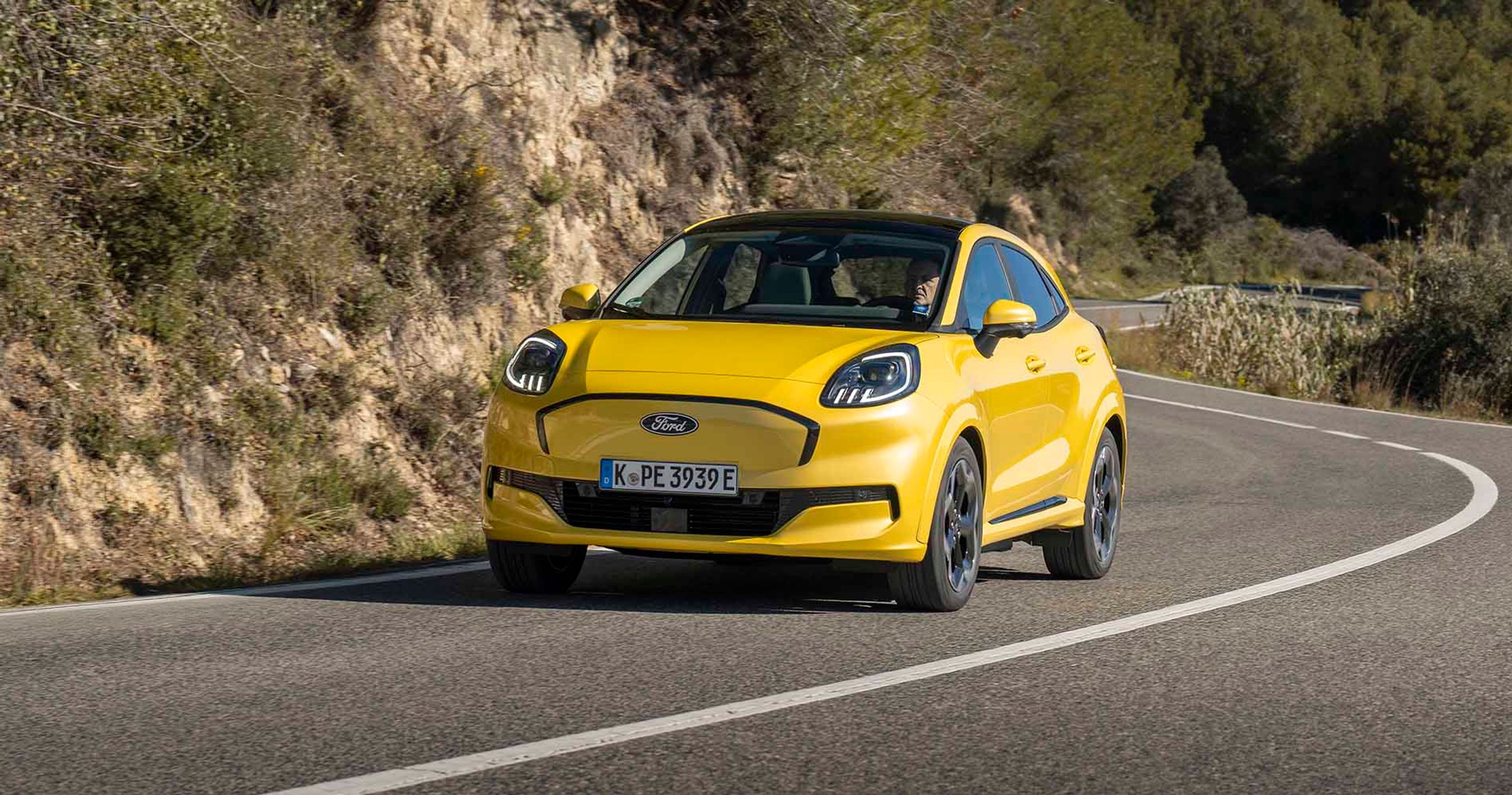 Gul Ford Puma set forfra kører i sving på bjergvej