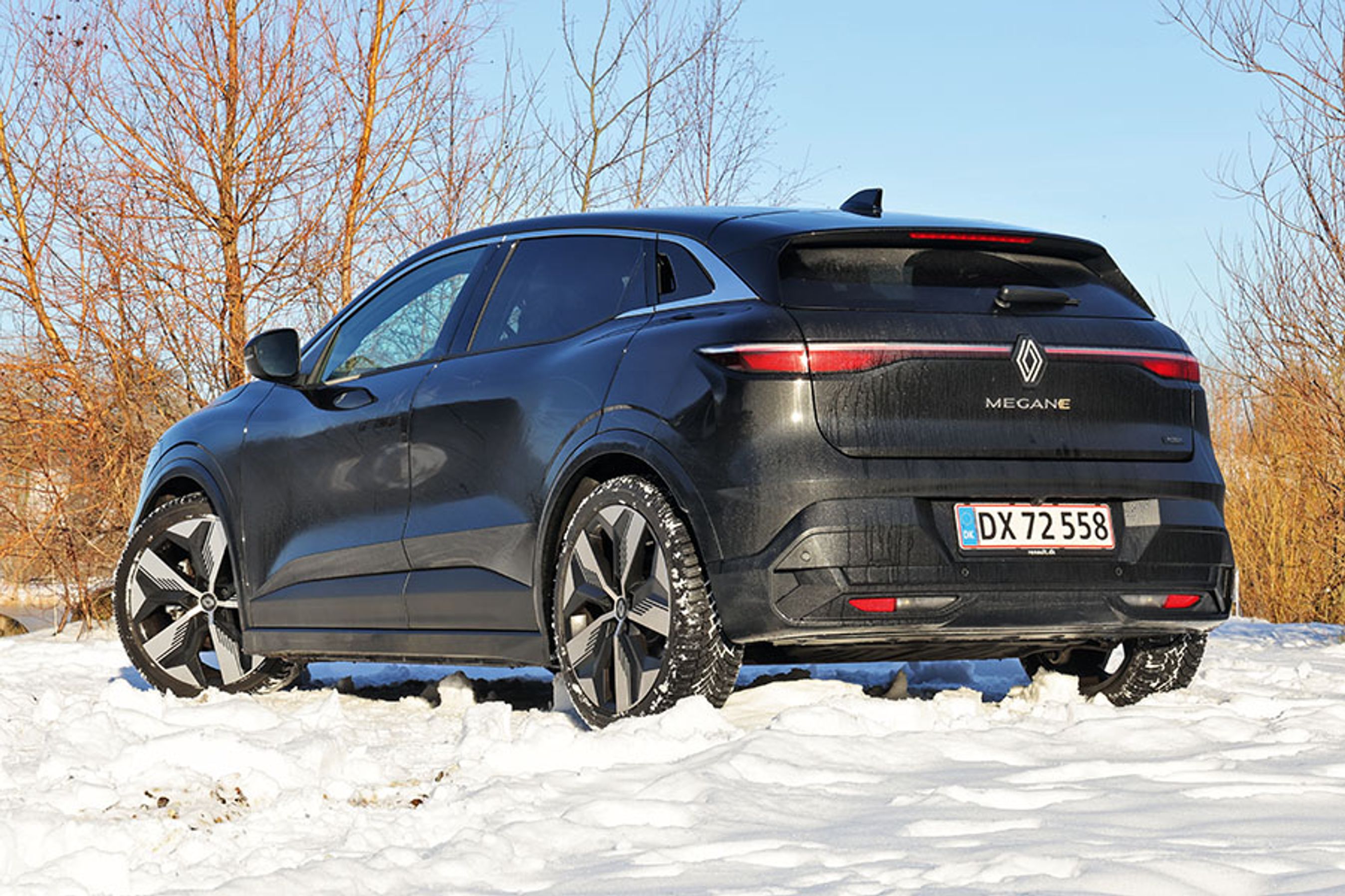 En sort Renault Megane set bagfra holder i sne med buske i baggrunden