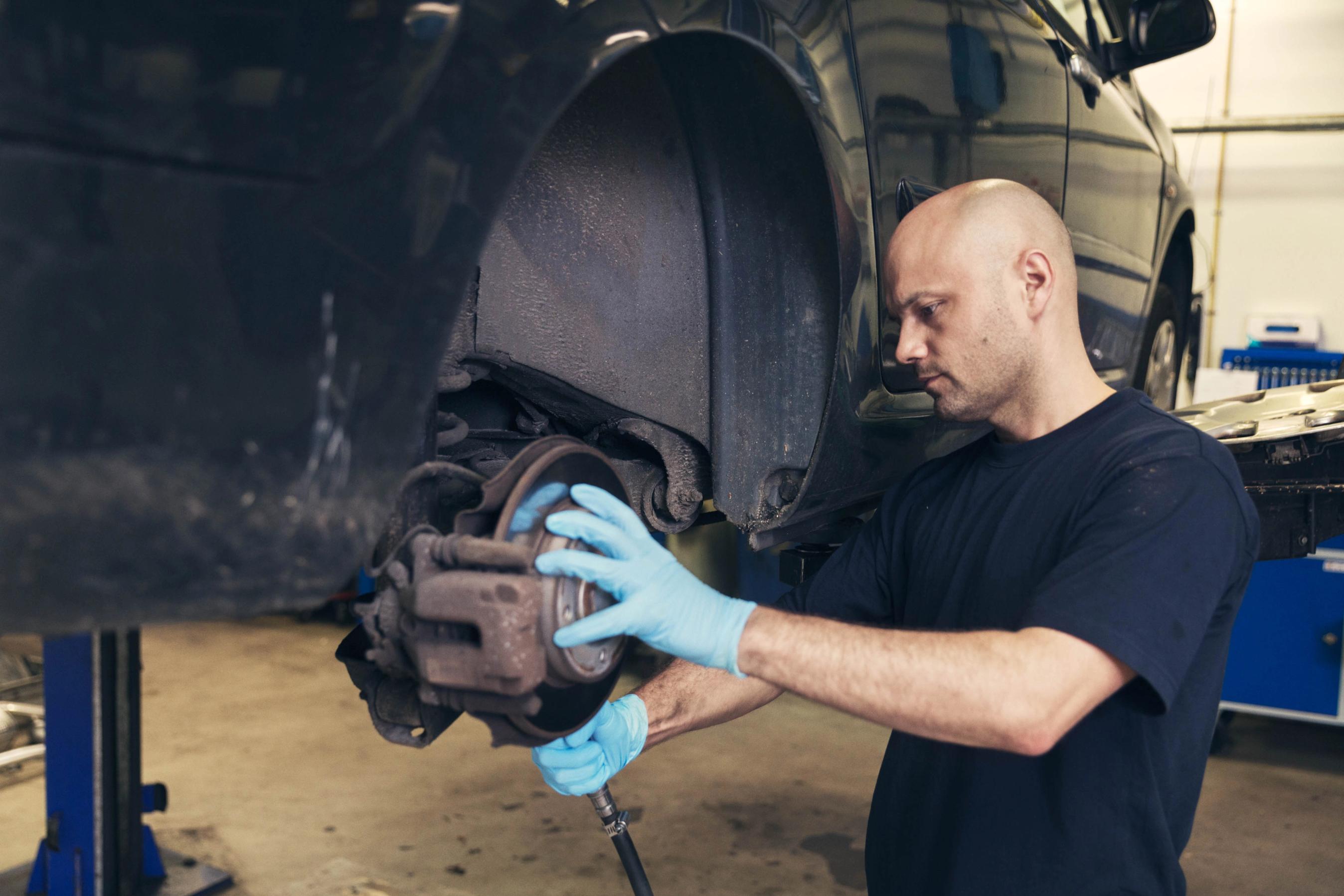 Bil er på værksted og har fået afmonteret sine hjul. 