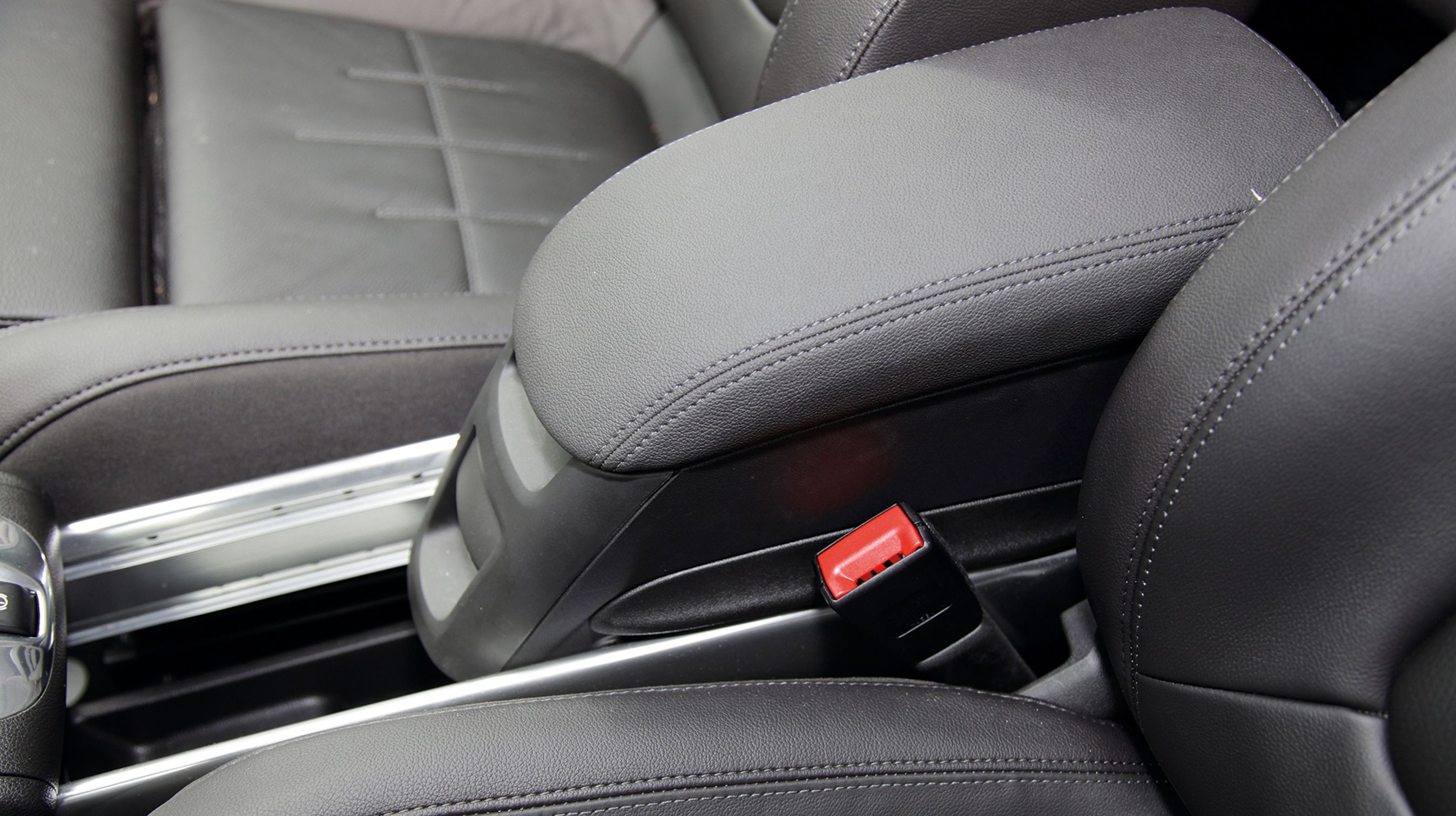 Mellem forsæderne er et midterarmlæn, der er monteret på en skinne, så det kan køres frem og tilbage efter behov. Man kan også afmontere armlænet og montere det ved bagsædet, hvis man ønsker det.