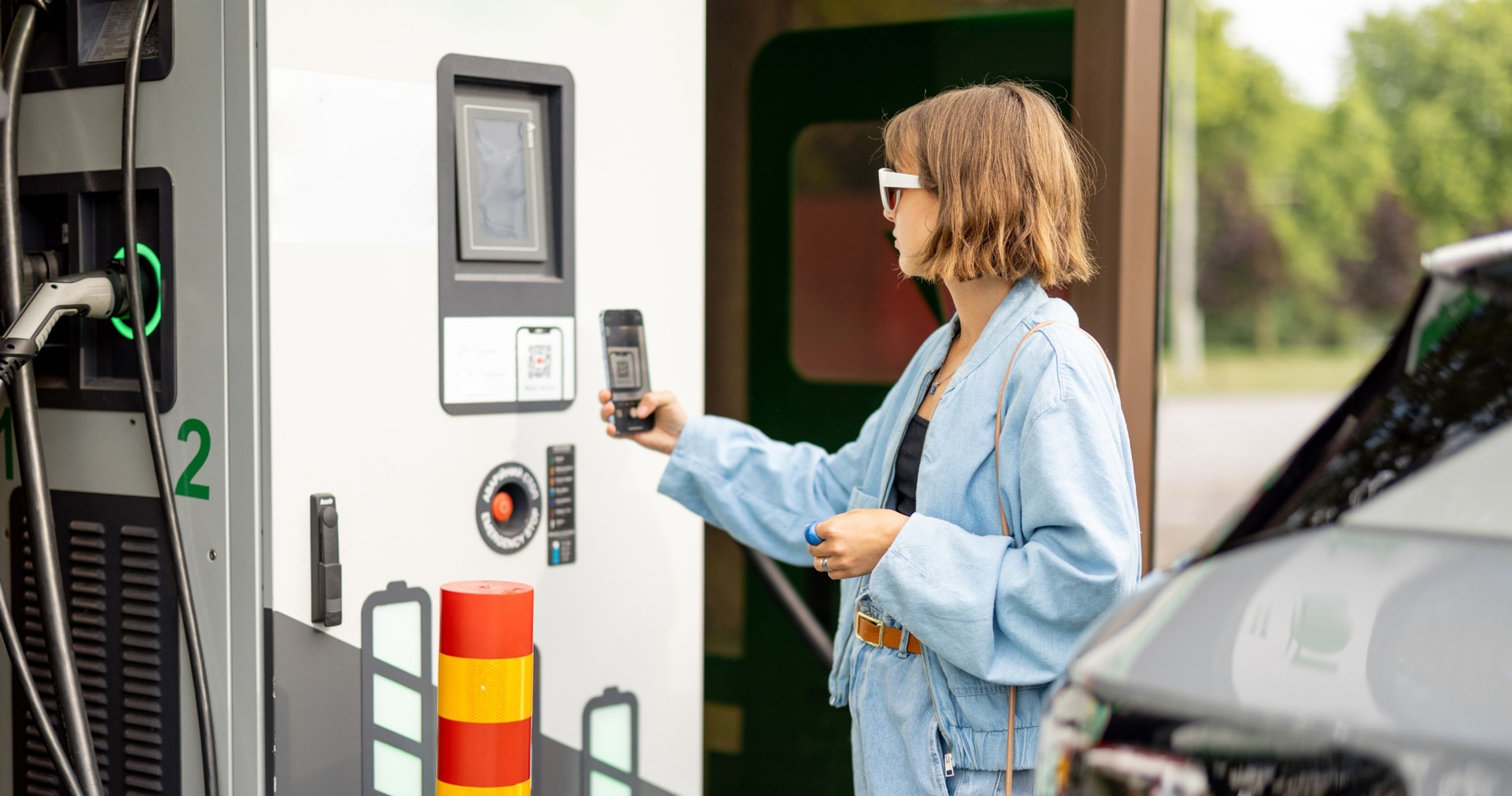 Kvinde scanner QR-kode ved ladestander