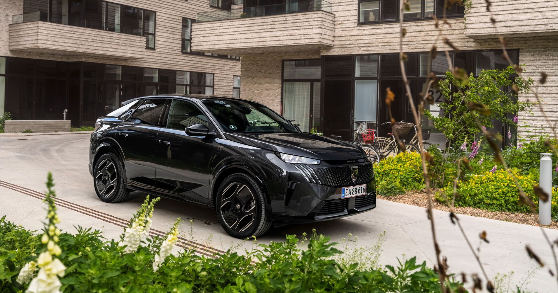 Bil kører på vej foran hus. 