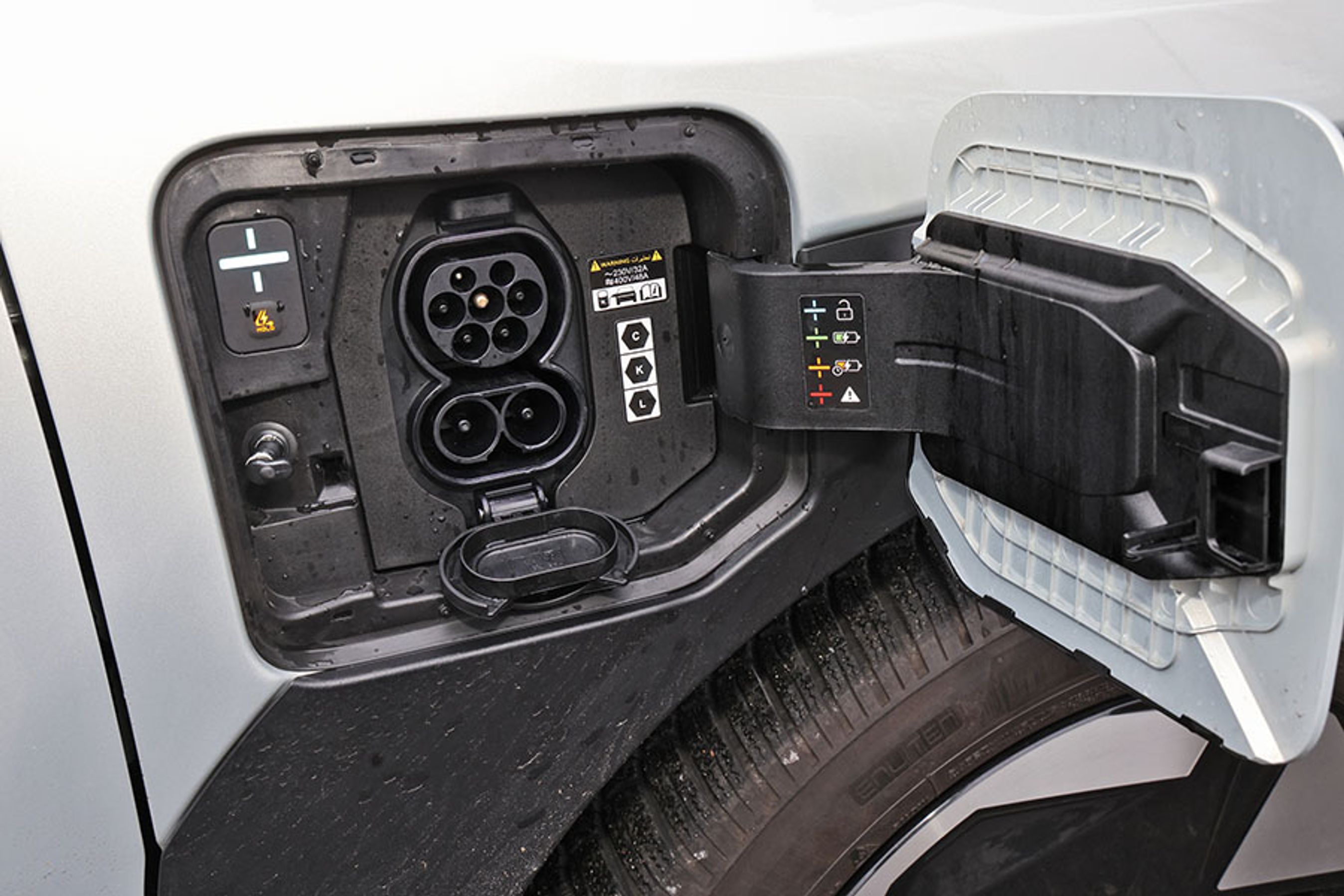 Ladelugen er placeret ved højre forhjul. Et vippelåg forneden er let at åbne, og der er separat knap til at frigøre ladekablet.