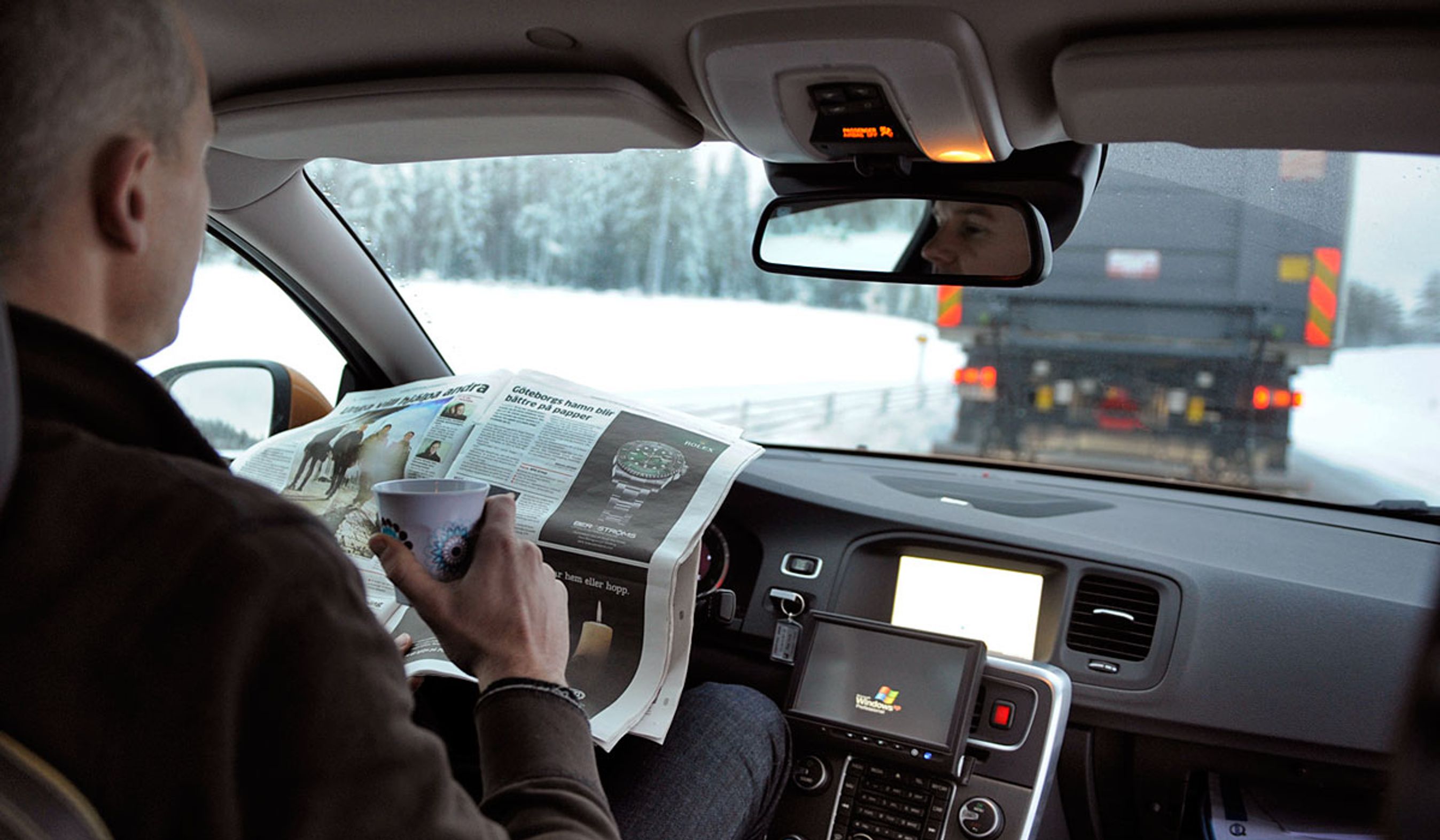 Uden hænder: Føreren i Volvo-testbilen kan læse avis, mens en lastbil "trækker" personbilen efter sig.