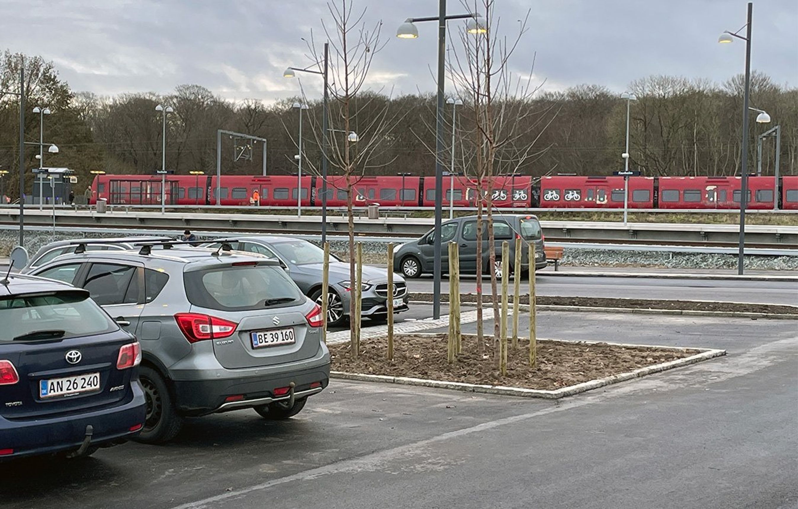 Skilt med 'Favrholm' i forgrunden og snedækket p-plads i bagggrunden. 