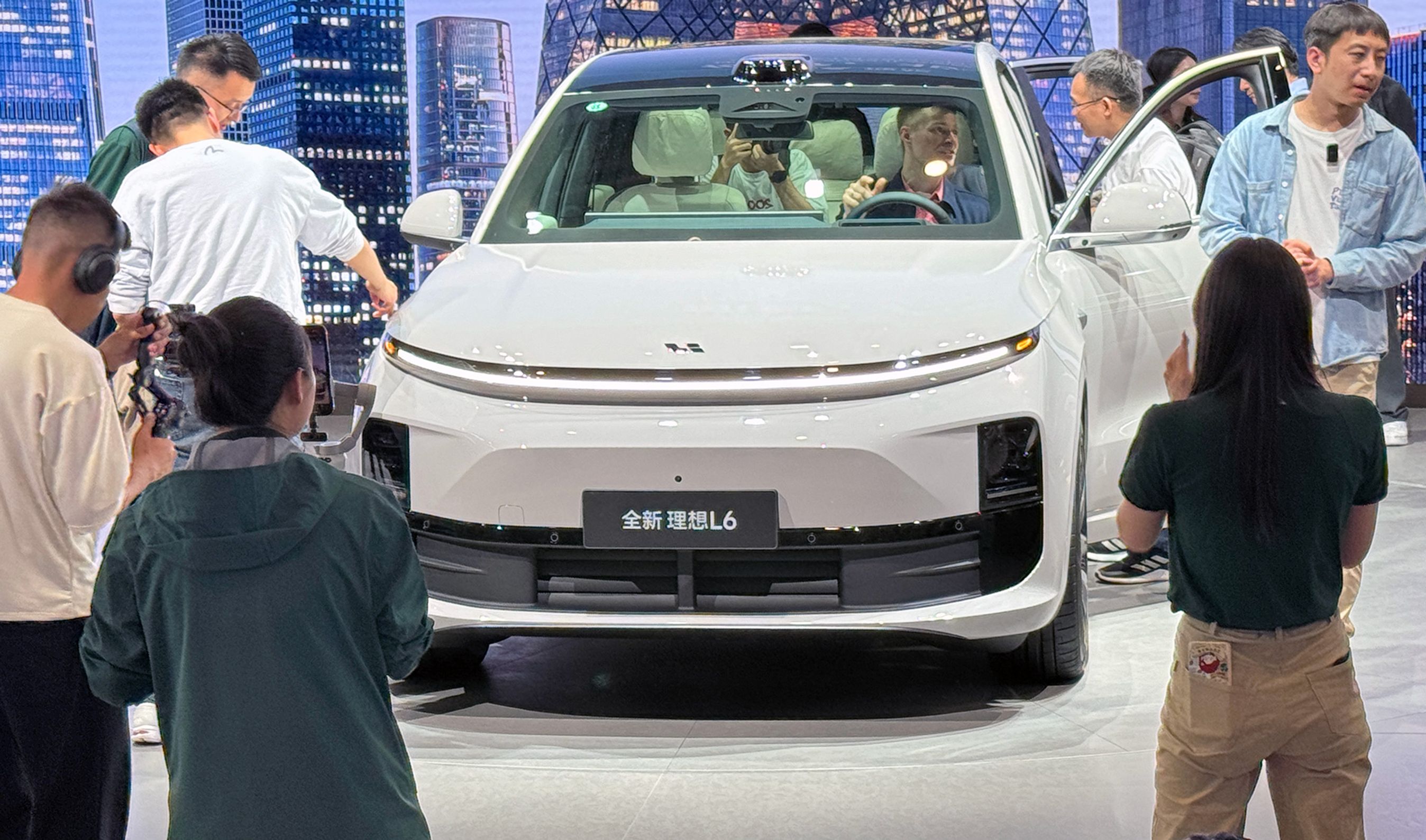 Hvid bil på scene omgivet af kinesiske tilskuere.