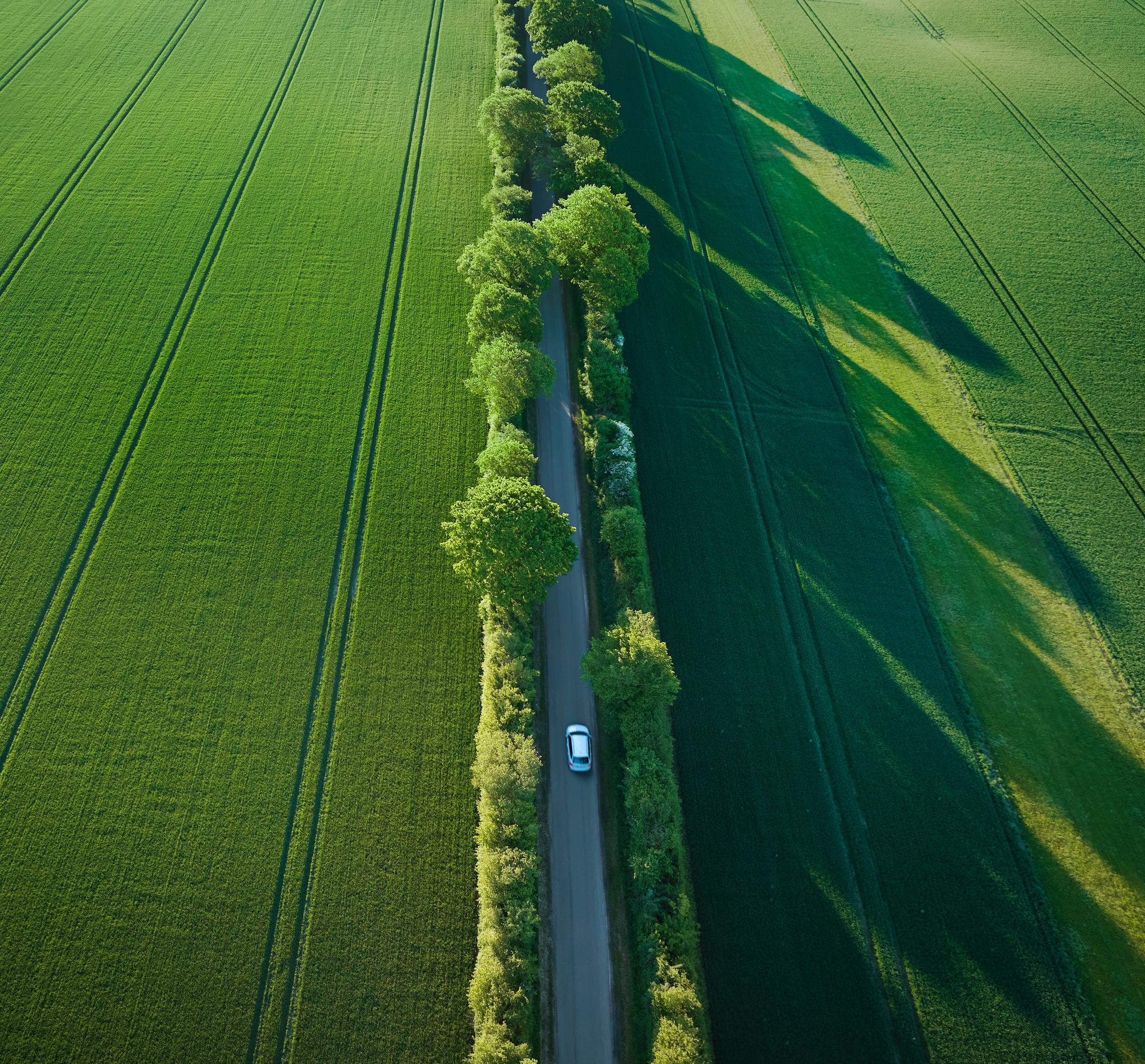 Bil set oppefra kører på landevej i sommersol