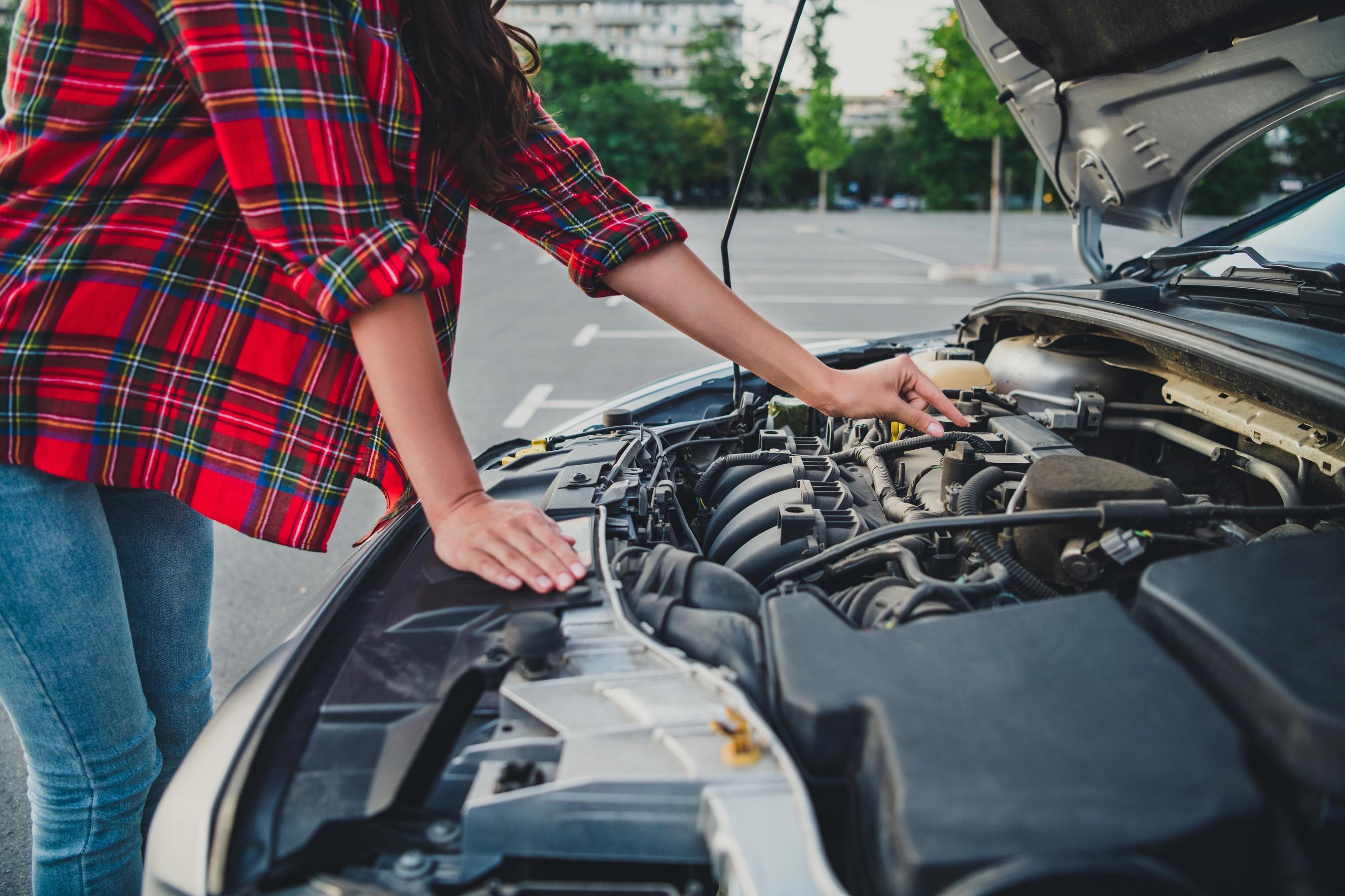 Motorrummet er åbent på en brændstofbil, og en personer forsøger at justere noget i motorrummet.