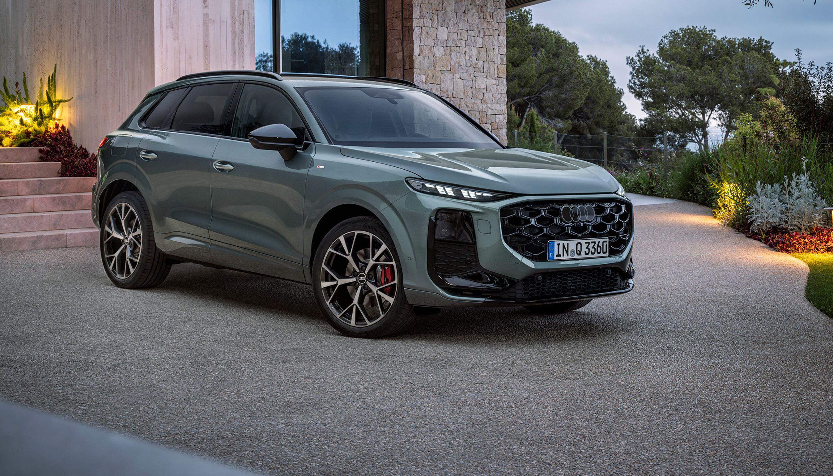 Audi Q3 skråt forfra foran villa i tusmørke.