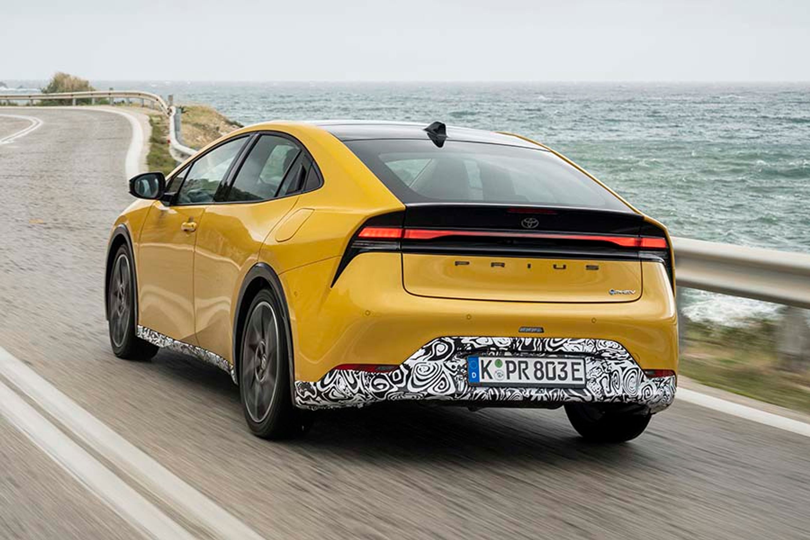 Der står ikke længere Toyota bag på bilen, men i stedet blot PRIUS med store, sorte bogstaver. Den særlige kamuflage skyldes, at vi fik mulighed for at køre bilen før den endelige lancering senere på året.