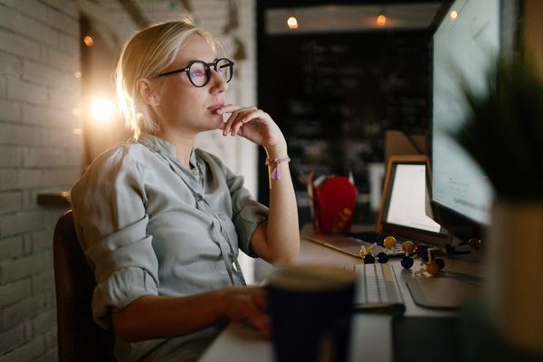 Thoughtful woman working at computer at night