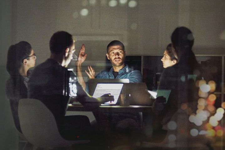 Team collaborating in dark boardroom late night meeting