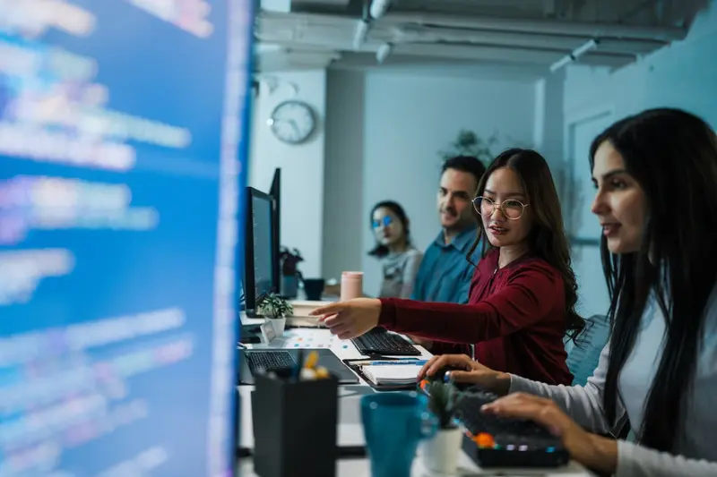 diverse developer team reviewing code on monitors