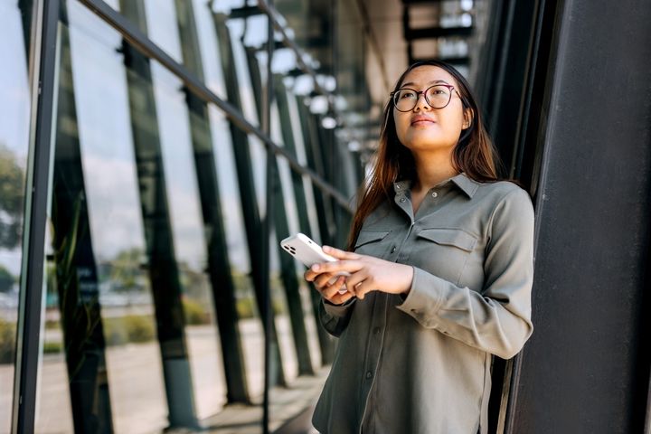 Woman with phone outside glass building