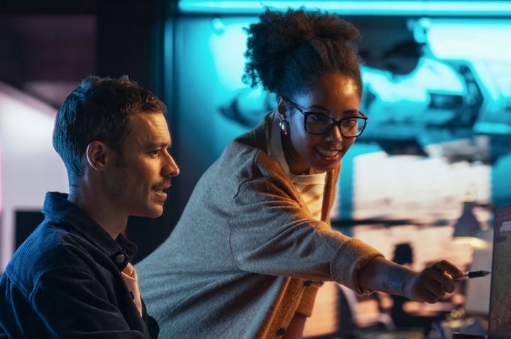 Two colleagues collaborating at computer gaming workstation