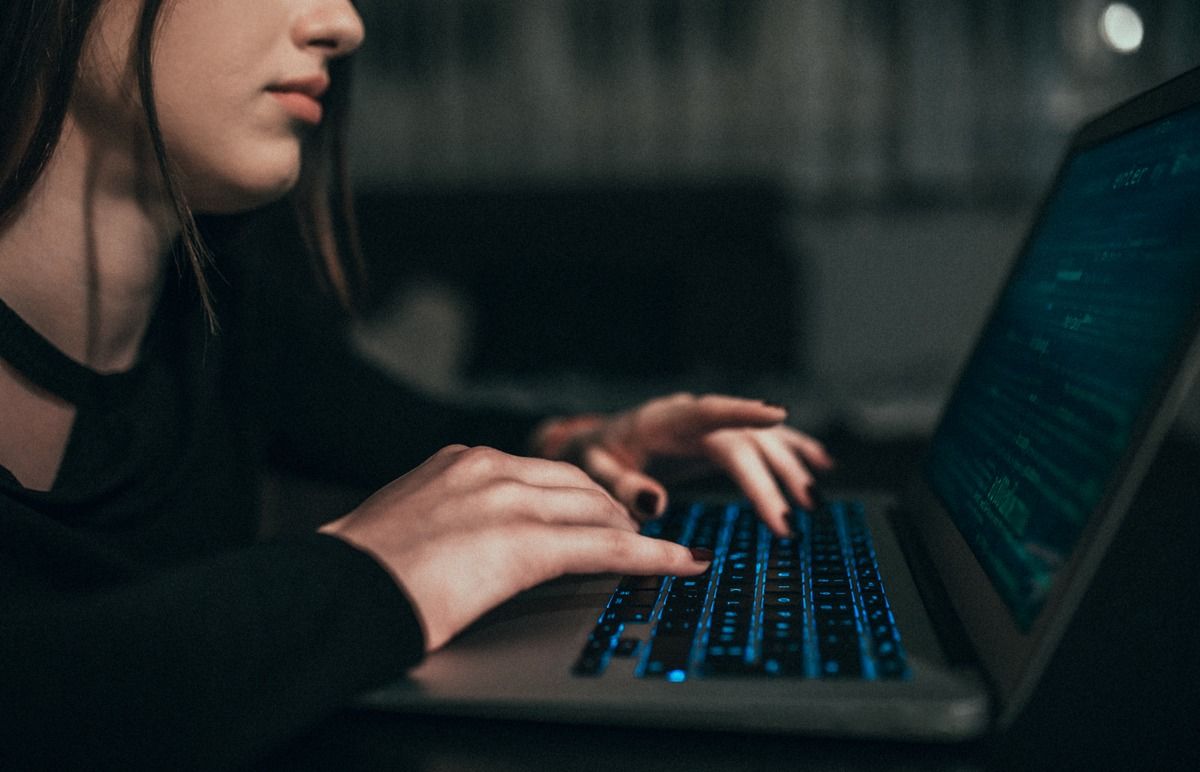 Hacker typing on glowing laptop in dark