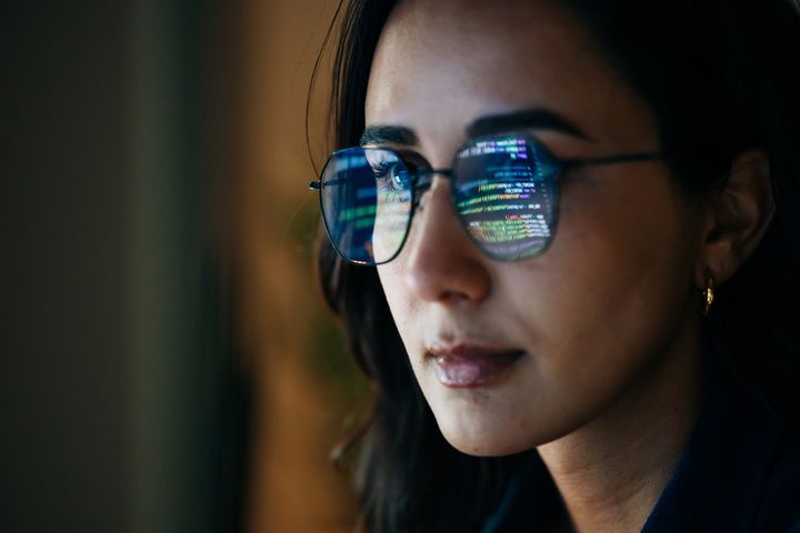 Close up female developer with code reflected in glasses