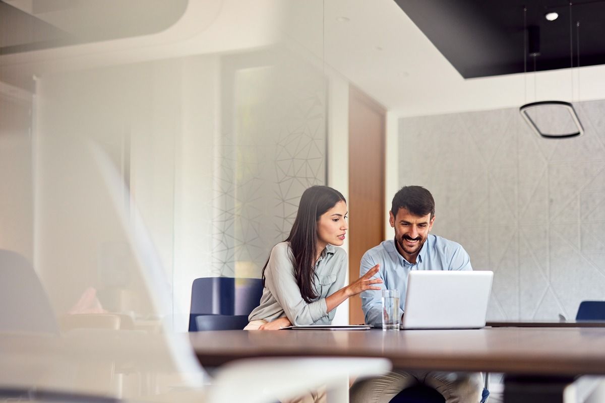 Two colleagues reviewing laptop in office