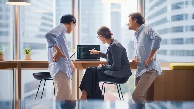 three developers collaborating around laptop in modern office